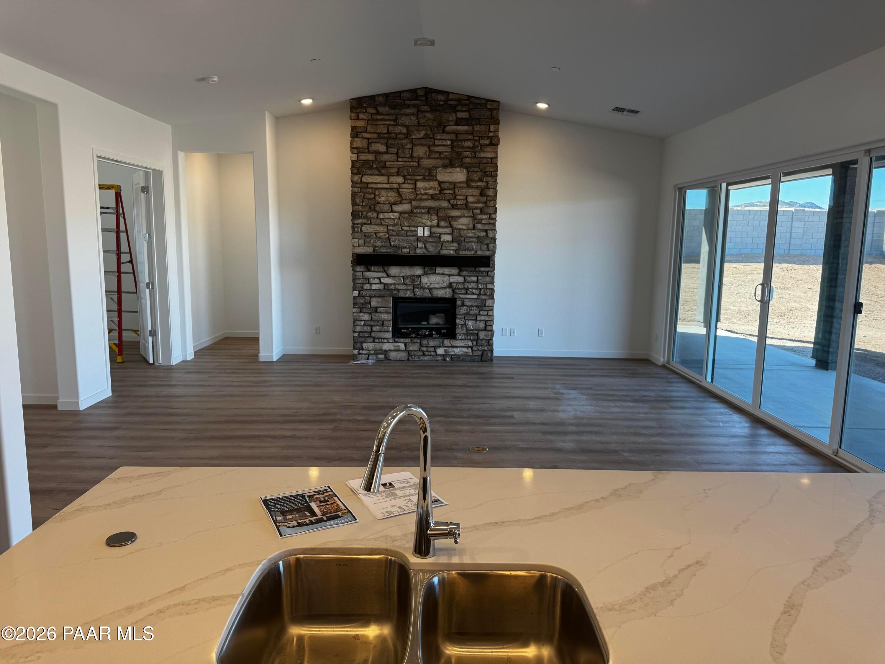 Open-concept great room with stacked stone fireplace, quartz island sink, and sliding doors in Davidson Homes The Blaze C, Prescott AZ