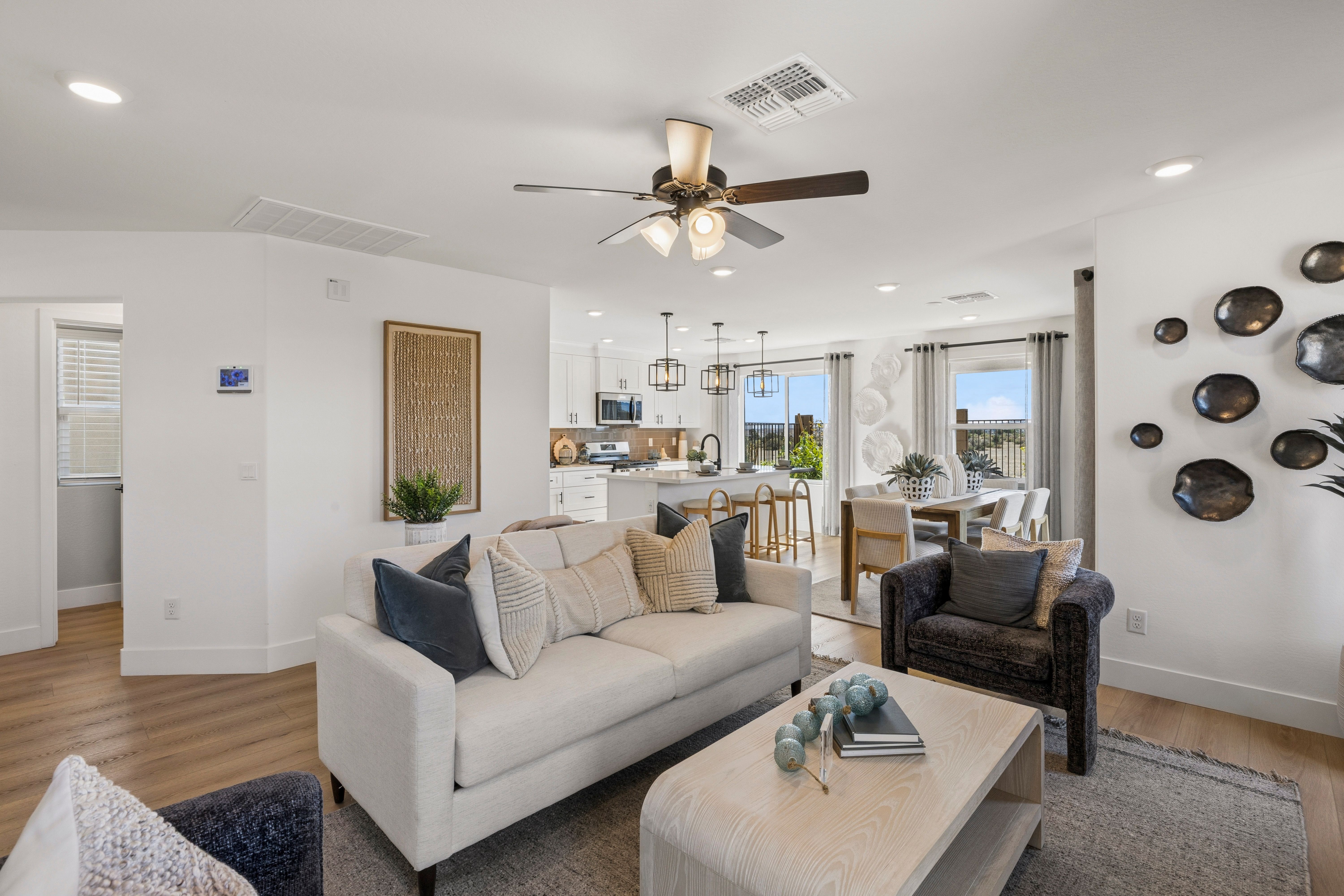 Open-concept living room and kitchen at South Ranch Southern Collection in Prescott AZ by Davidson Homes with white sofa, hardwood floors, ceiling fan