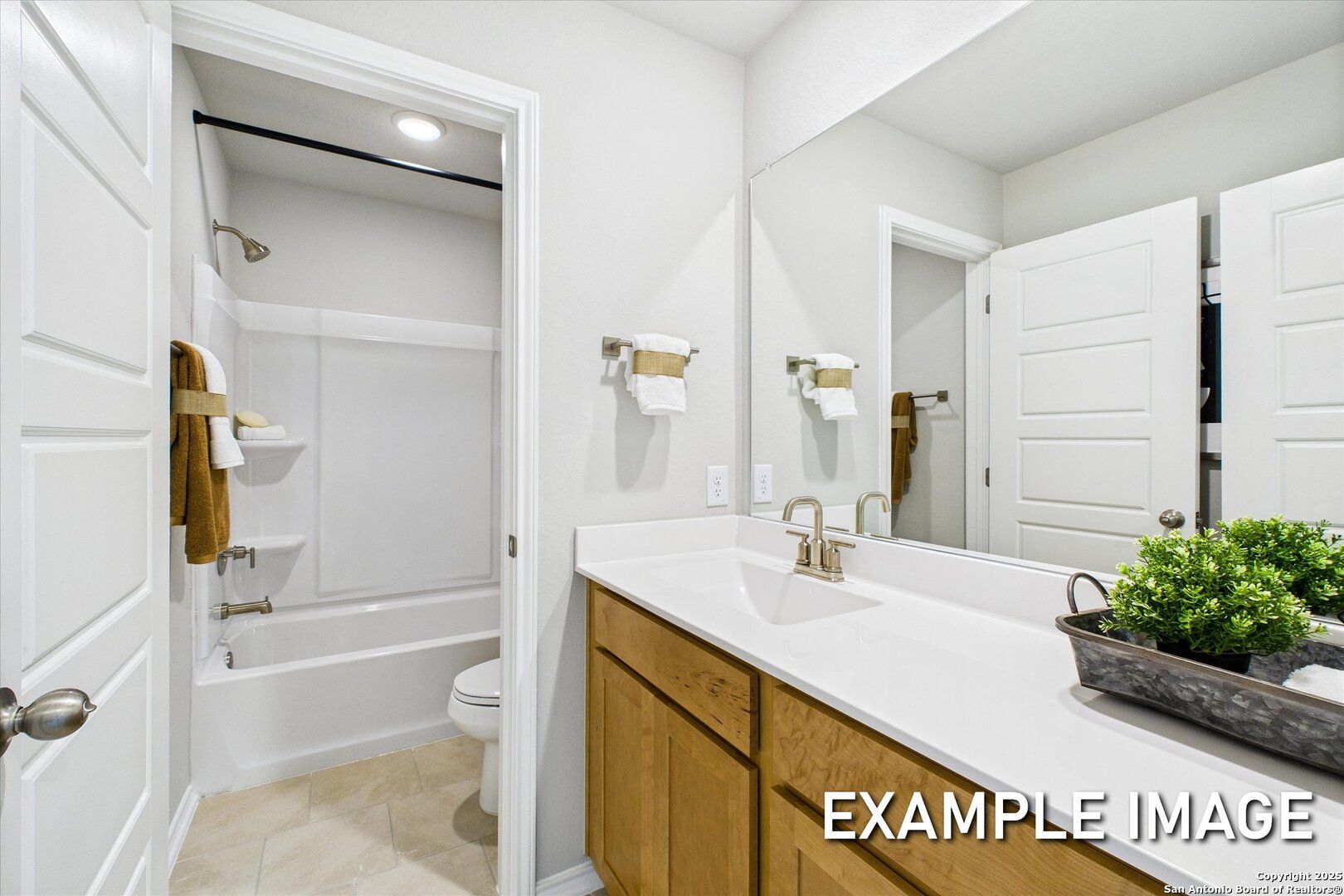 Bright bathroom with tub-shower combo, oak vanity, and white tile in Davidson Homes Sabine C, Agave, San Antonio