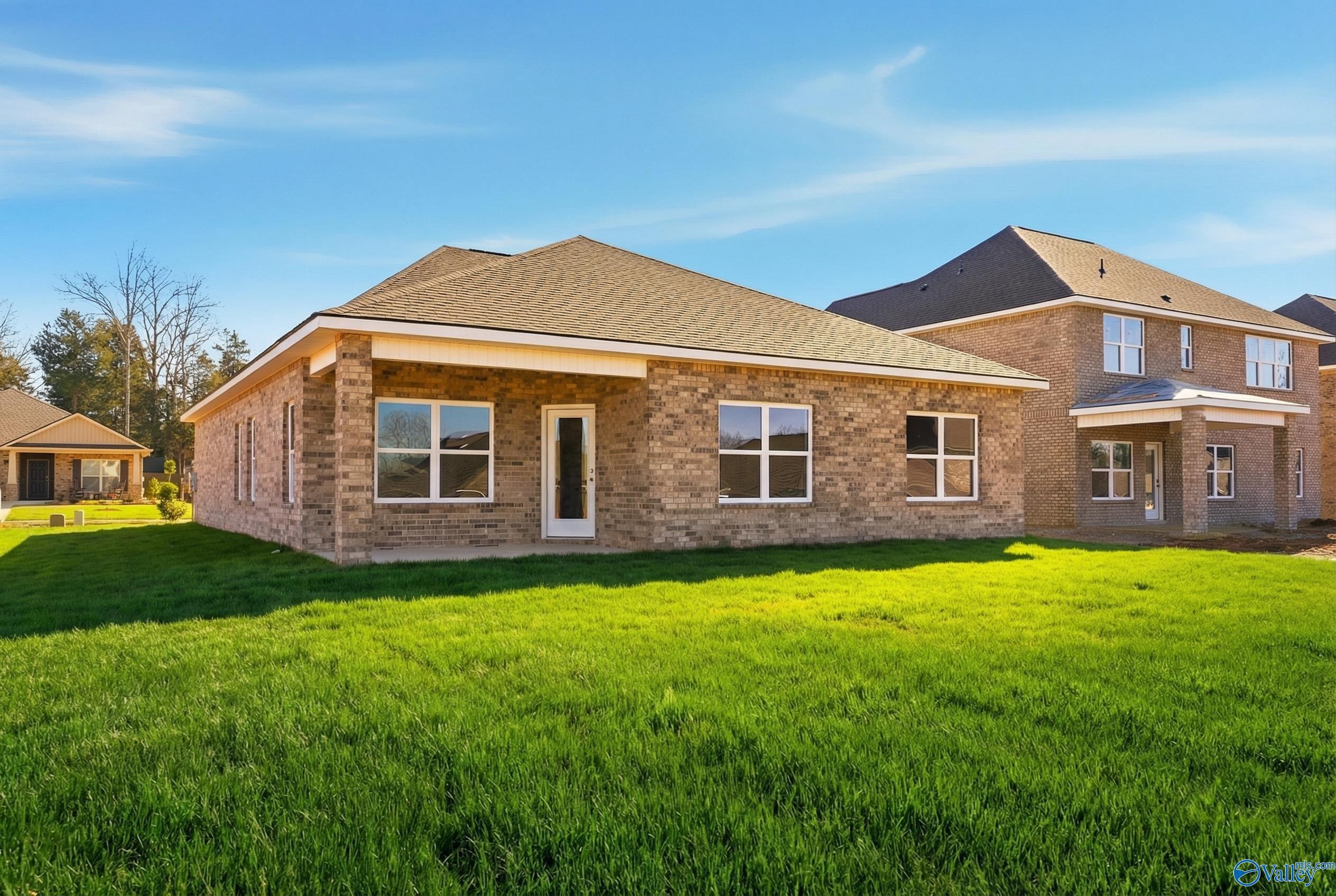 Single-story brick home with 2-car garage, beige trim, and lush green lawn in Creek Grove, New Market, Alabama