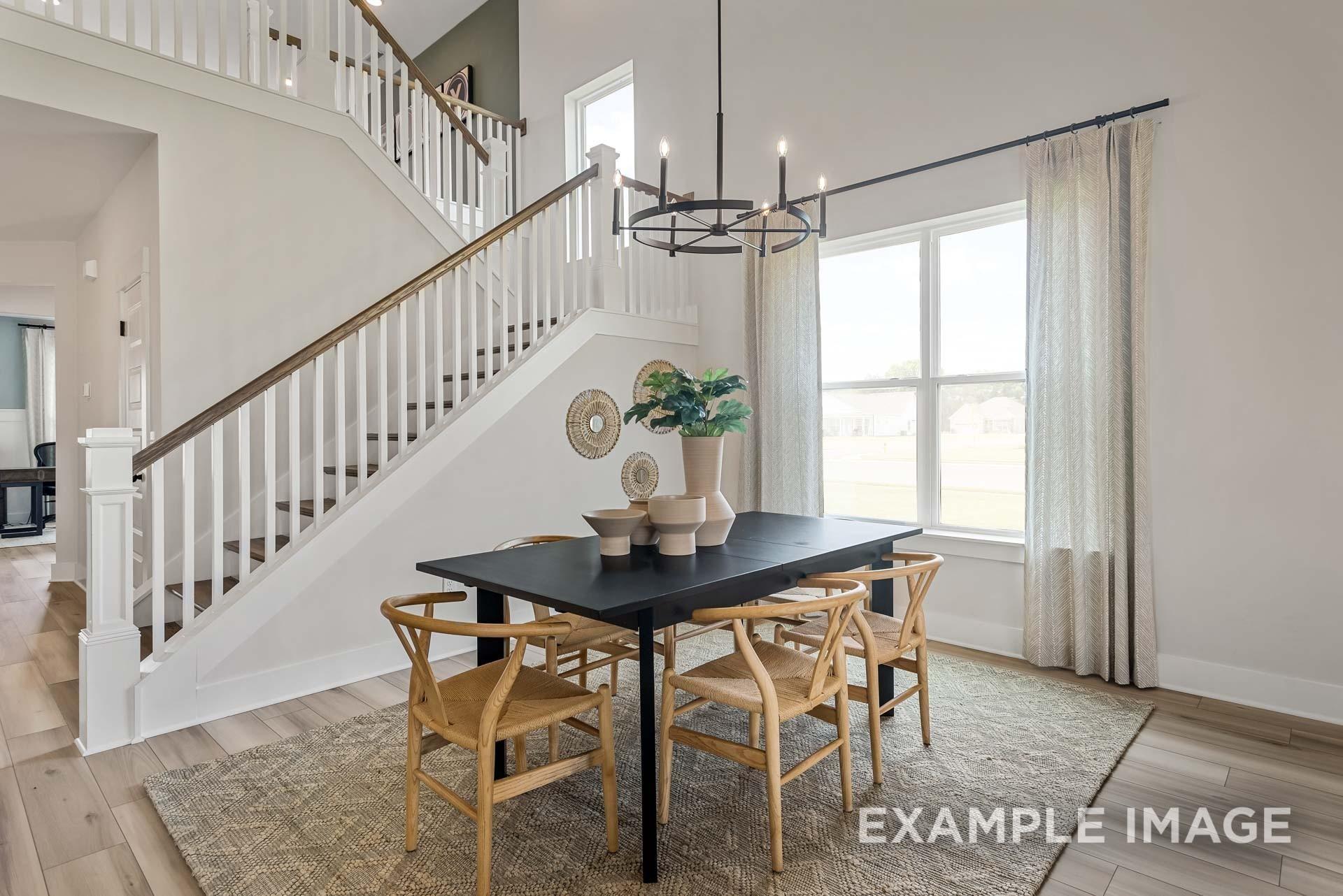 Elegant dining room with black rectangular table, woven chairs, chandelier, and staircase in Davidson Homes The Ridgeport, Gallatin, TN