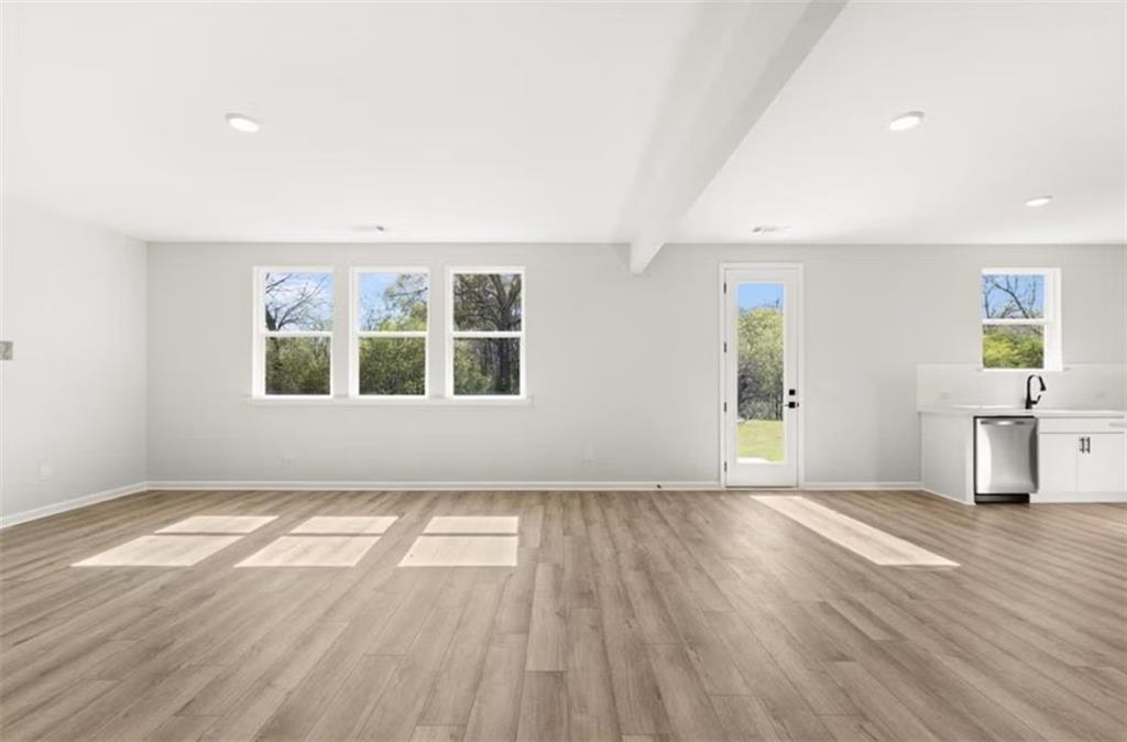Bright empty great room with hardwood floors, large windows, French door to backyard in 5-bedroom Hickory B home, Winder GA