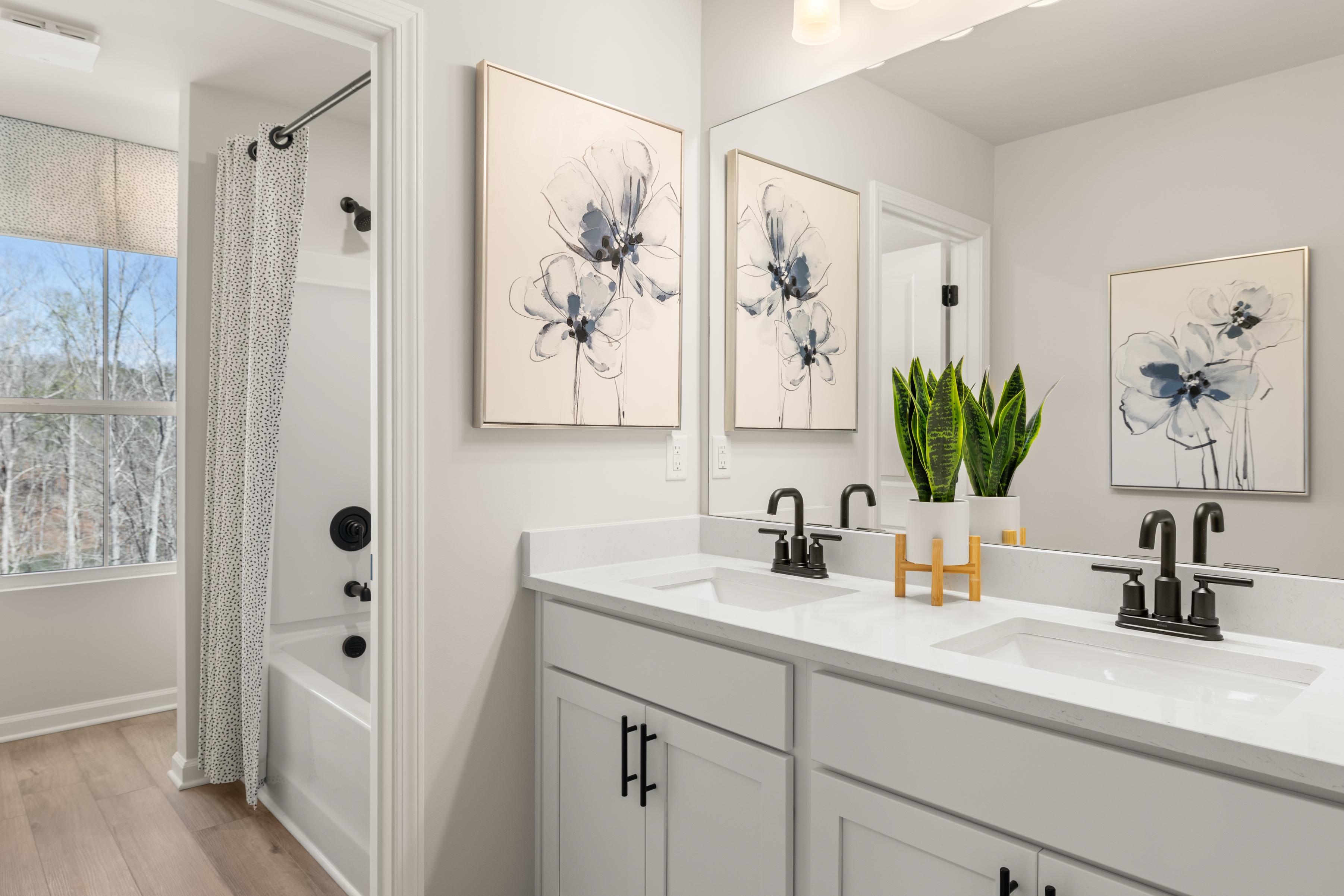 Spacious primary bathroom at The Bluffs in Canton GA with double vanity, floral art, and potted plant