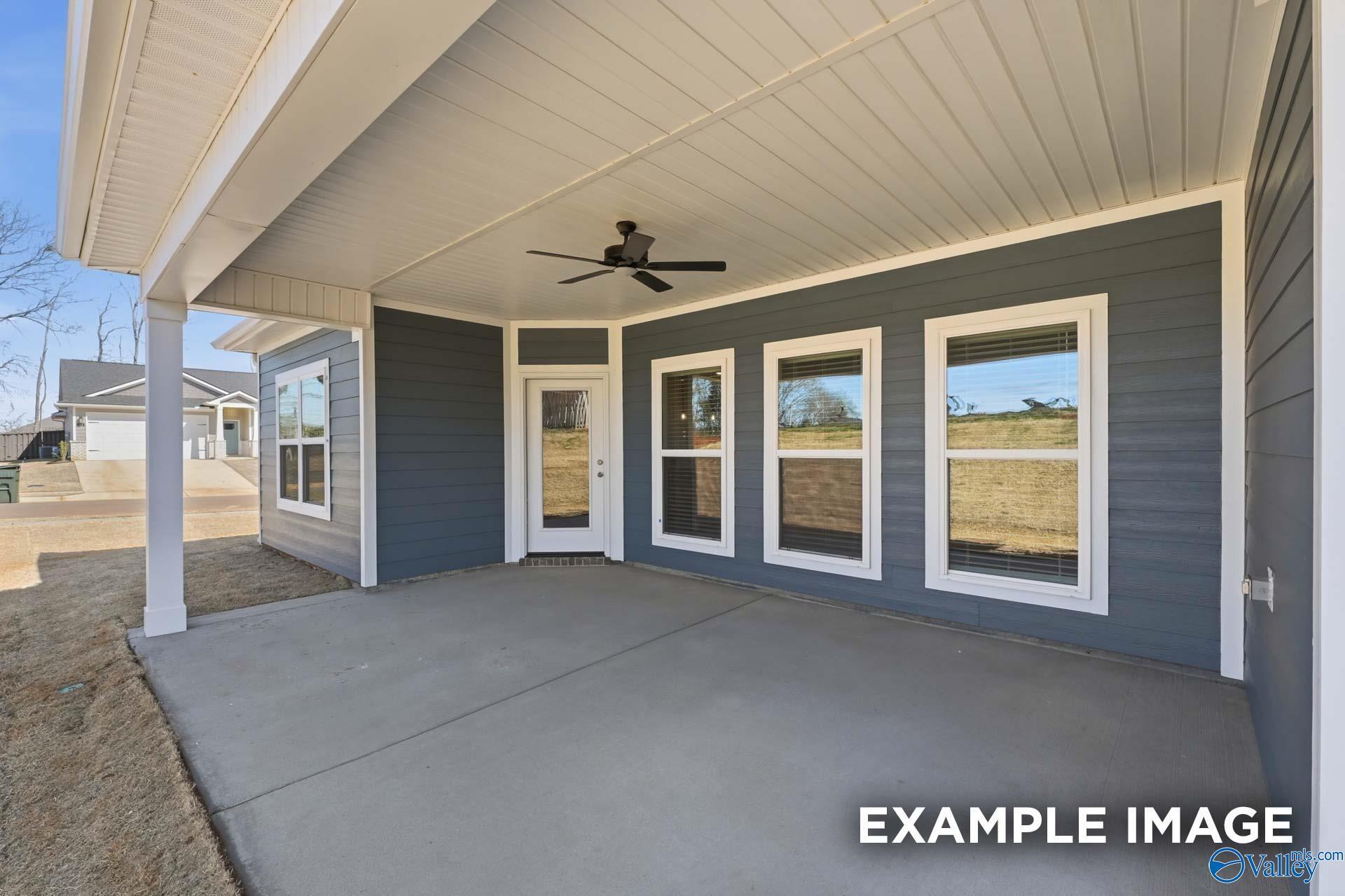 Covered patio with ceiling fan, large windows, and concrete slab in gray-sided Davidson Homes The Harrison C, Madison, Alabama