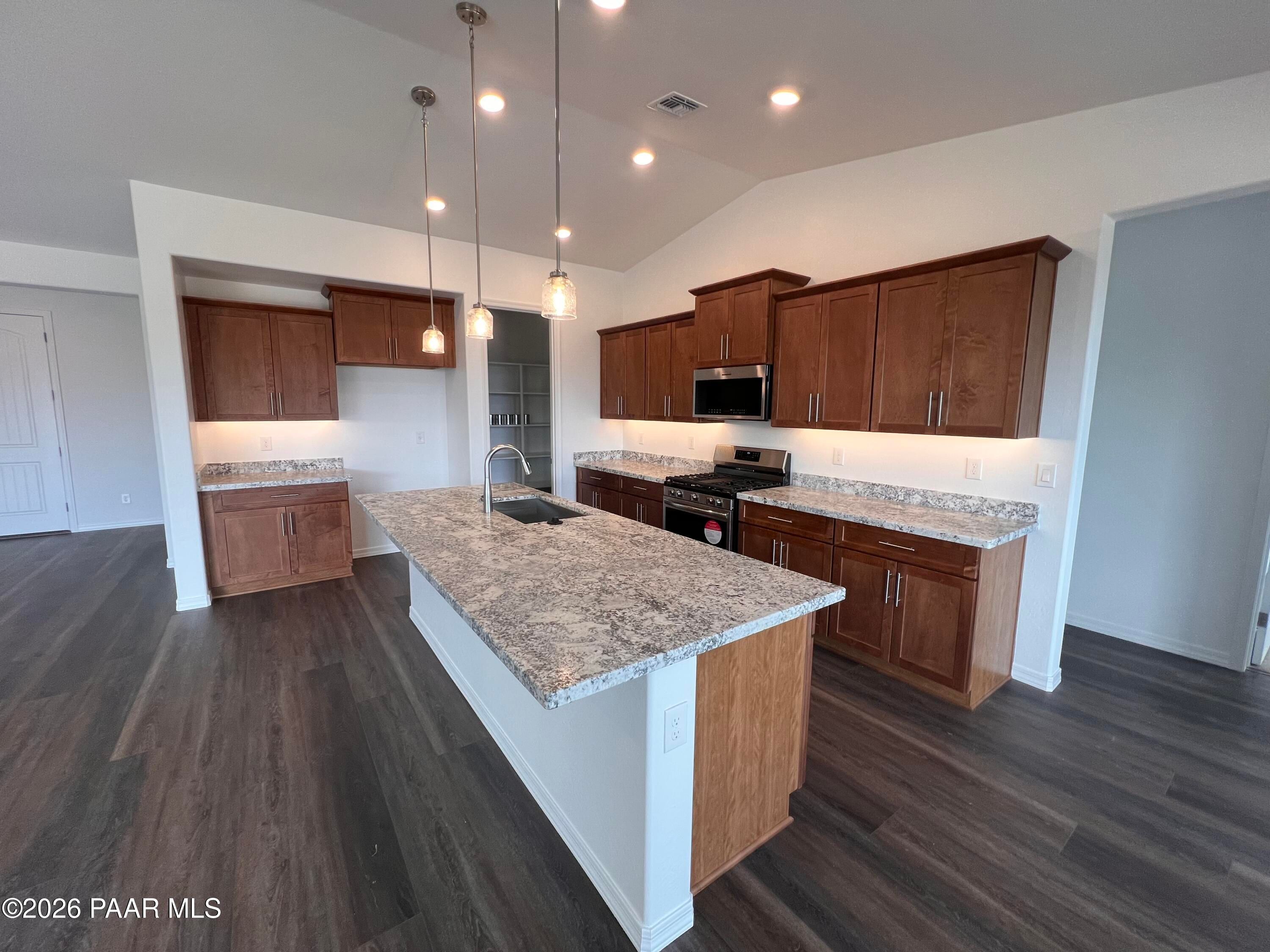 Spacious open-concept kitchen with granite island, stainless appliances, and wood cabinets in Davidson Homes The Monarch A, Prescott AZ