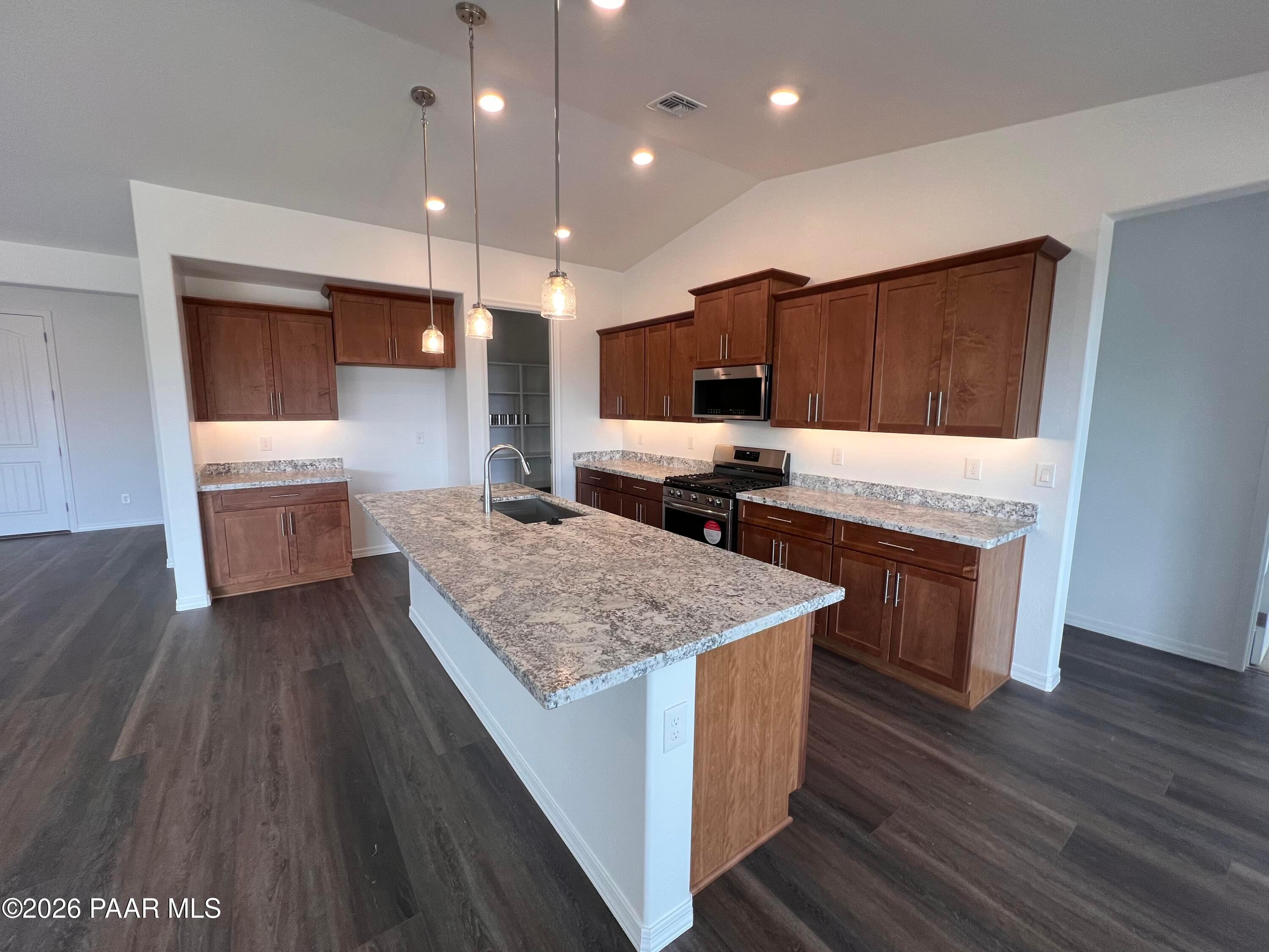 Spacious open-concept kitchen with granite island, stainless appliances, and wood cabinets in Davidson Homes The Monarch A, Prescott AZ
