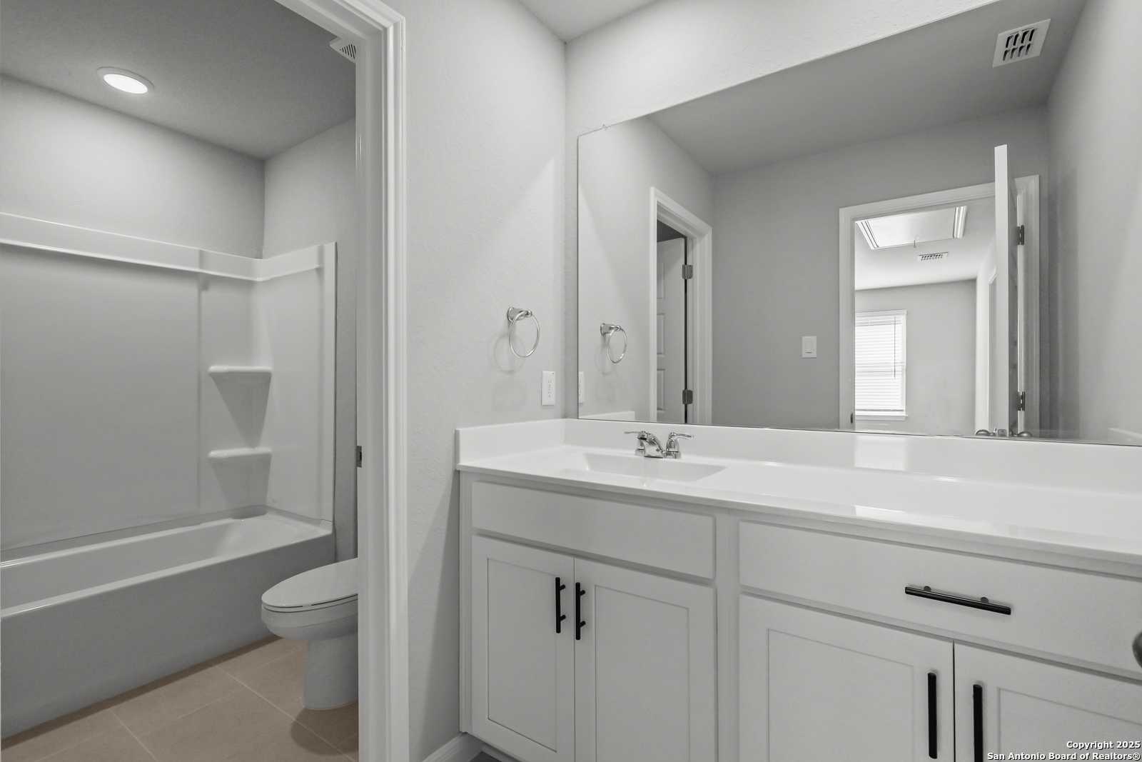 Modern master bath with dual sinks, freestanding tub, glass shower, and walk-in closet access in Davidson Homes Gillian C, San Antonio, TX