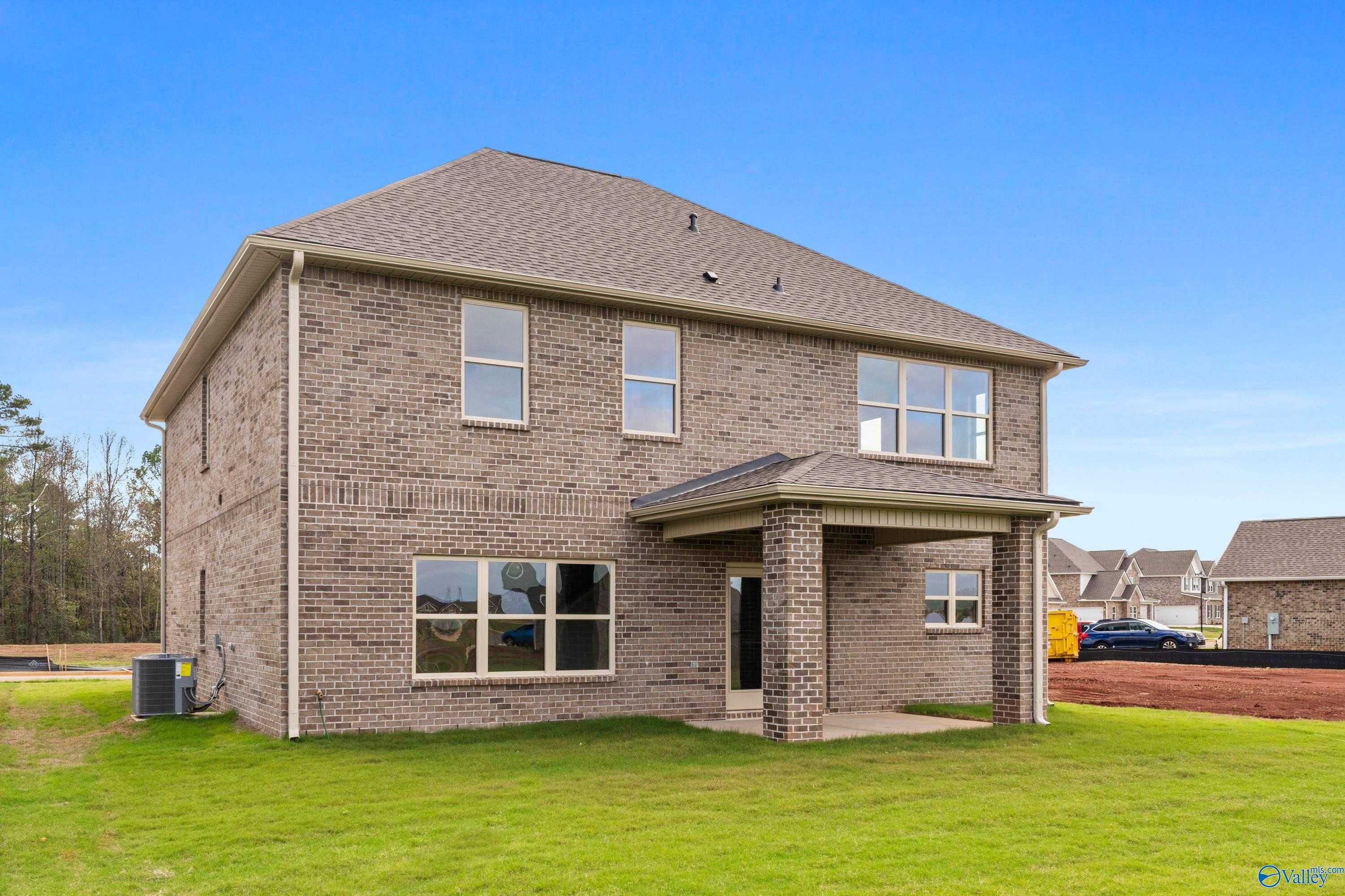 Two-story brick home with gabled roof, covered porch, and green lawn in Creekside, Harvest, Alabama by Davidson Homes