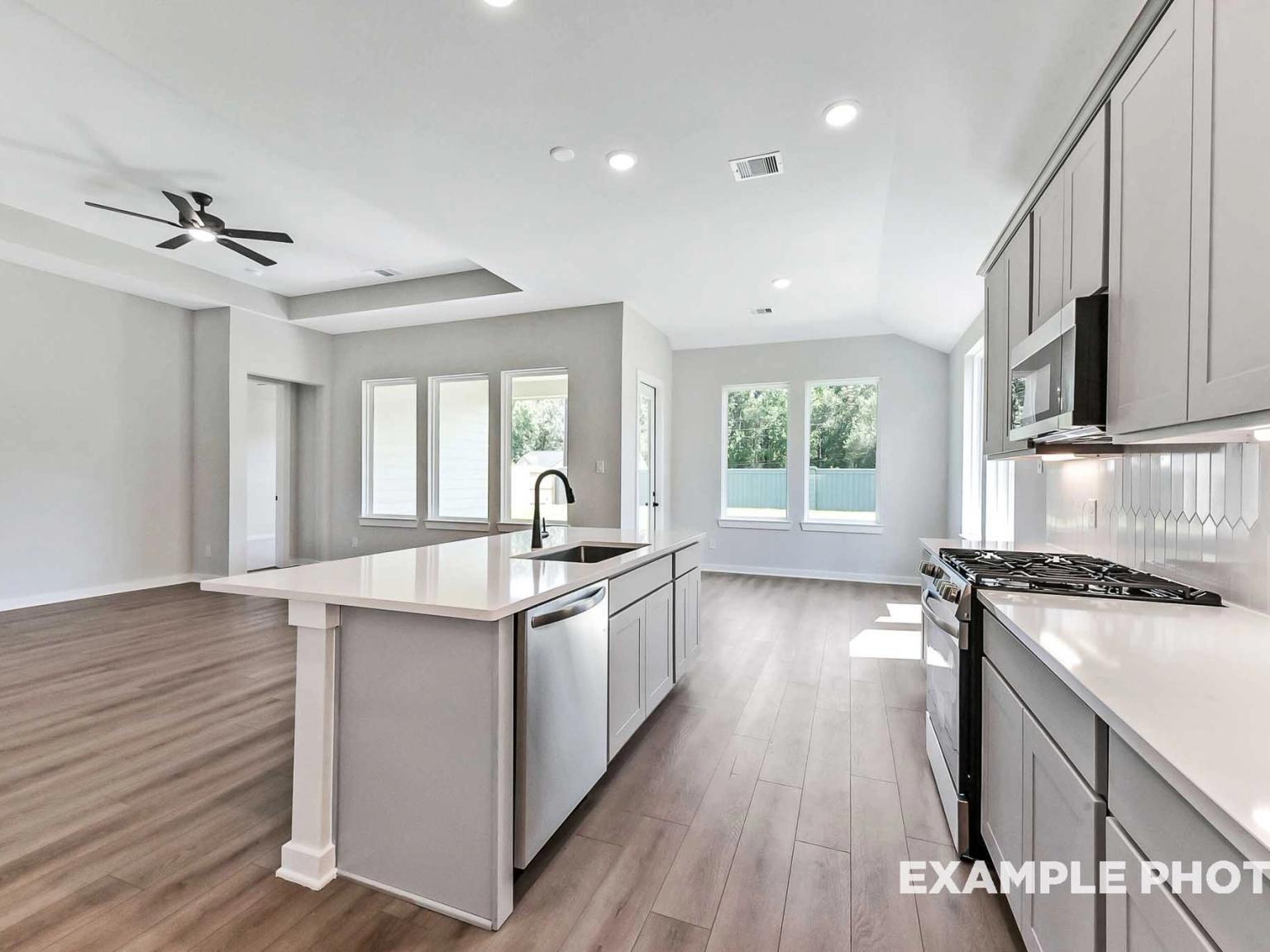 Modern open-concept kitchen with large island and stainless appliances in The Sequoia C floor plan at Sundance Cove, Crosby.