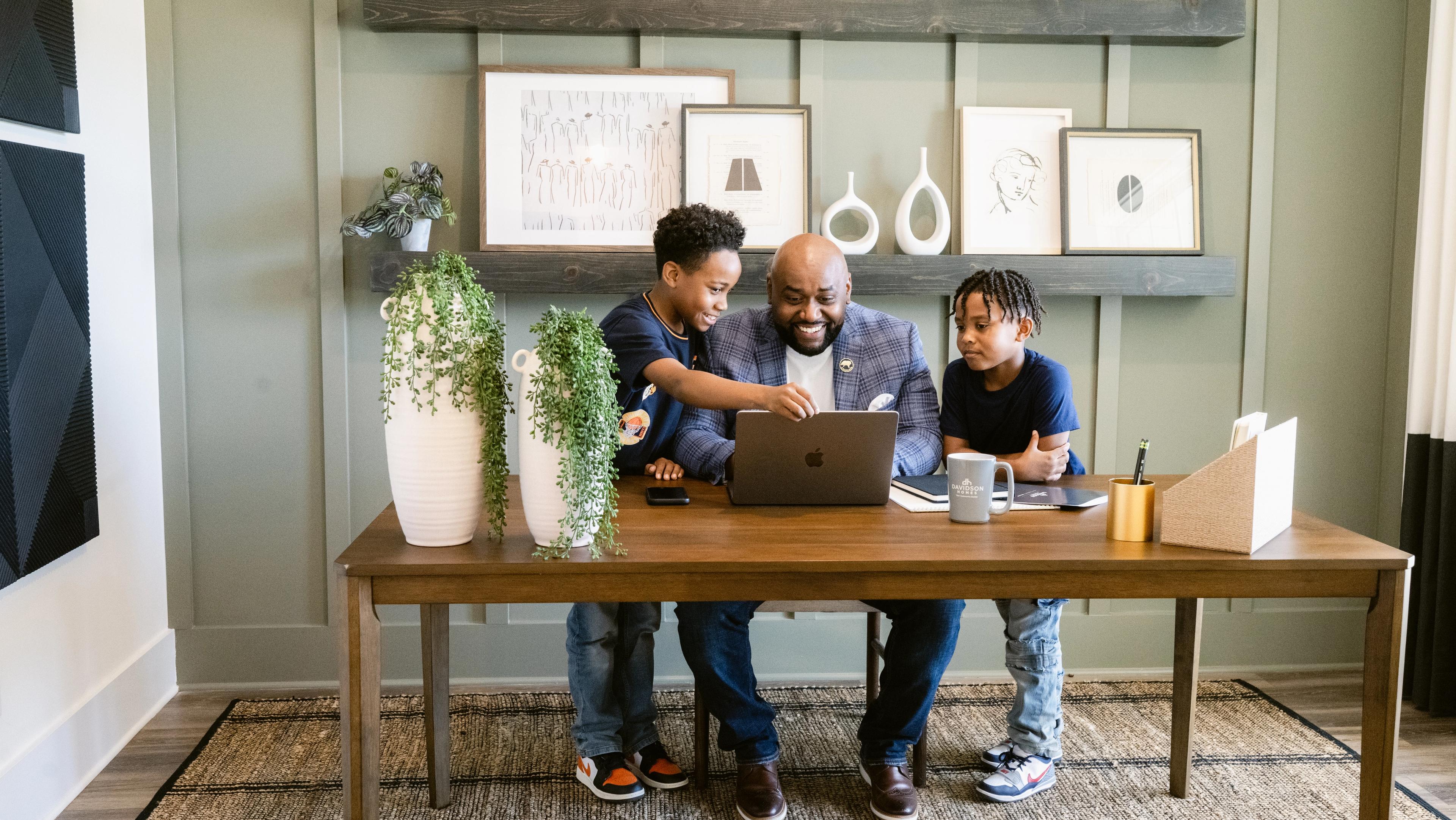 Father and two children looking at a laptop together in a new home office
