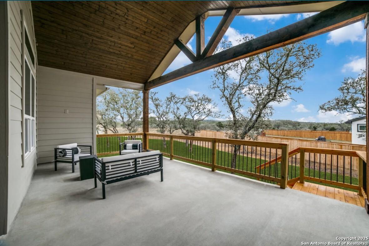 Covered back patio with vaulted wooden ceiling, outdoor seating, and lush green yard in Davidson Homes The Garner B, Ladera, San Antonio