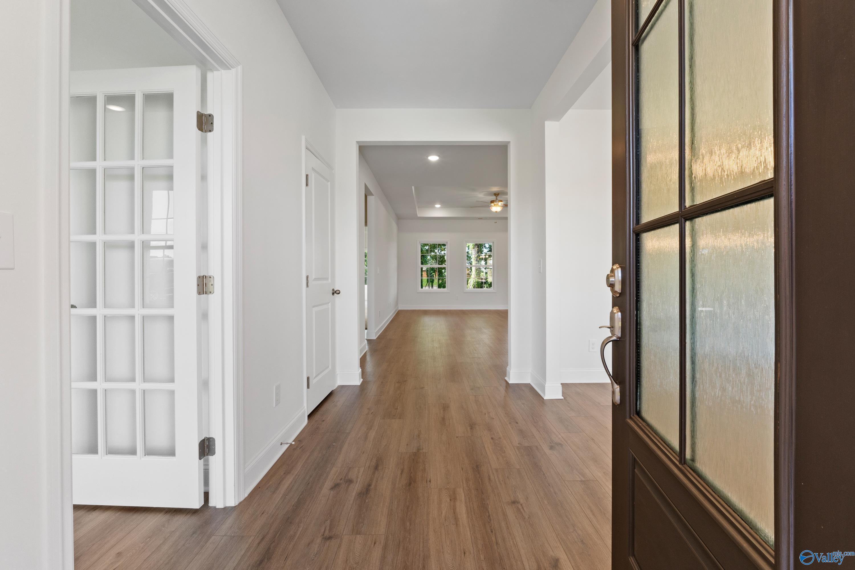 Bright entry hallway with hardwood floors, white doors, and frosted glass front door in Davidson Homes The Oxford, Creekside, Harvest AL