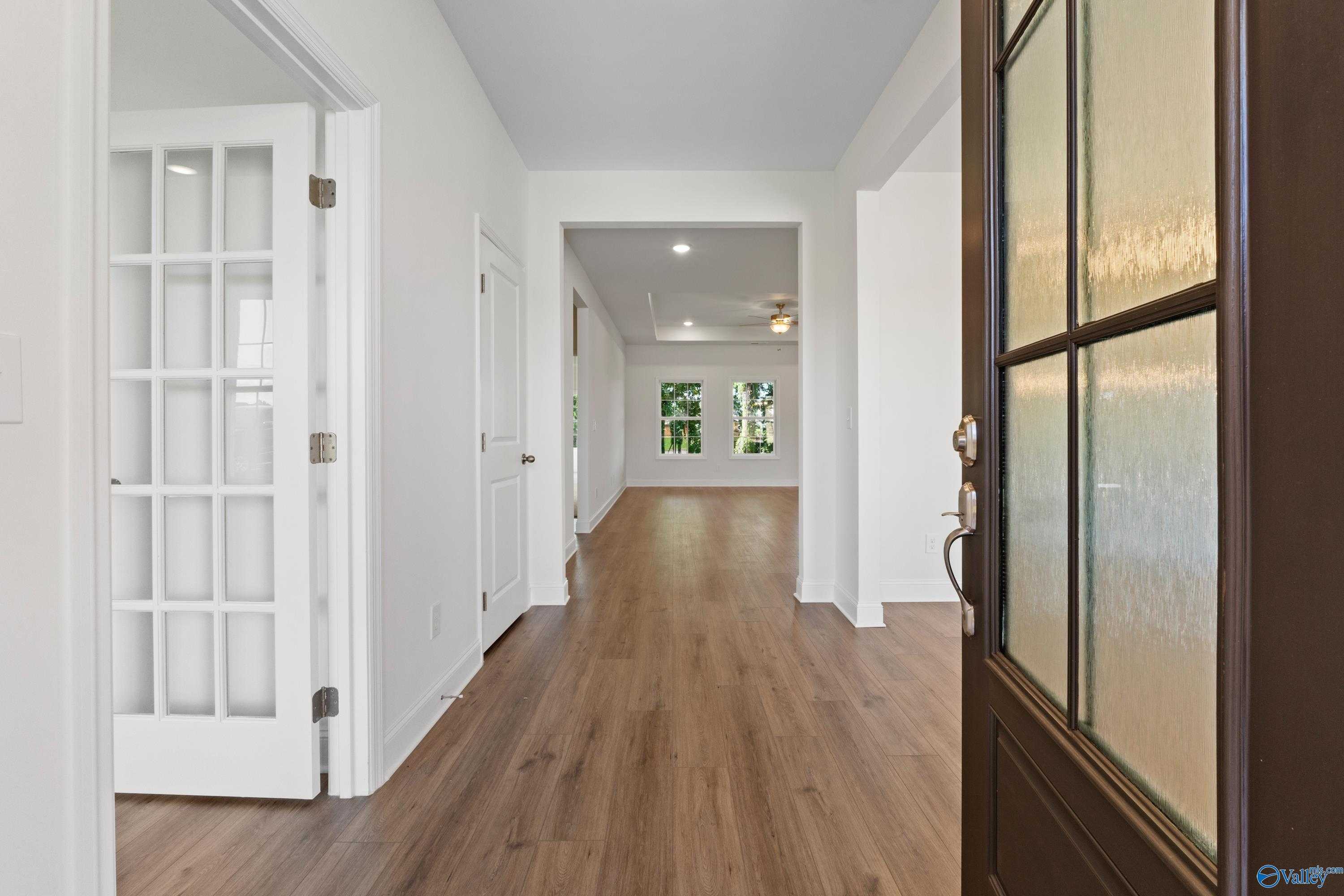 Bright entry hallway with hardwood floors, white doors, and frosted glass front door in Davidson Homes The Oxford, Creekside, Harvest AL