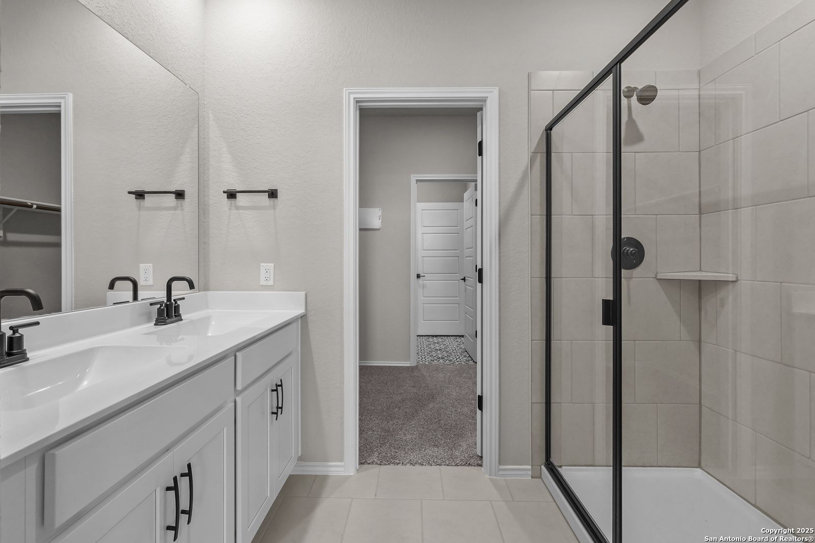 Modern master bathroom with double white vanity, chrome faucets, mirrors, and glass shower in Davidson Homes The Brazos C, San Antonio