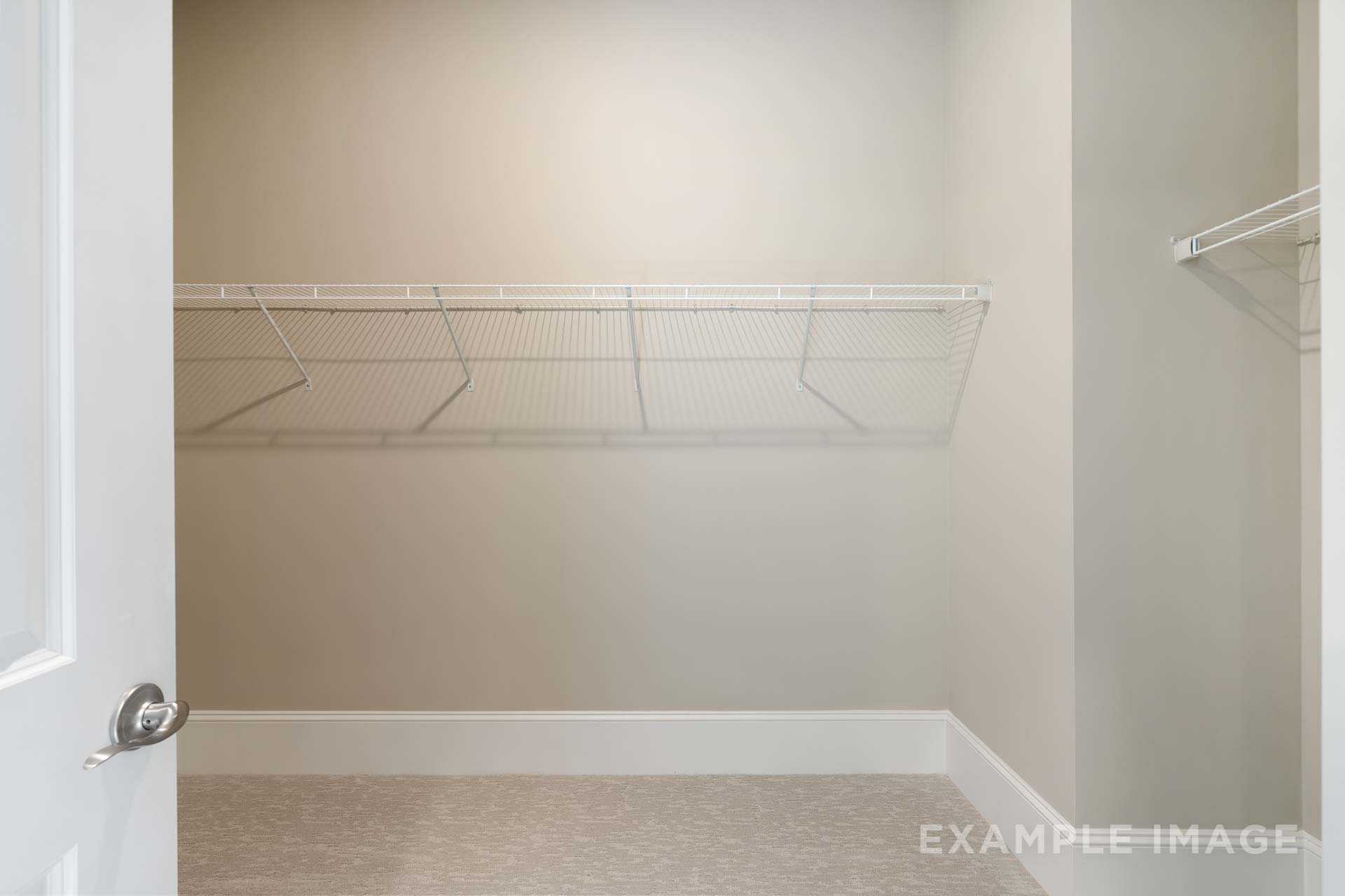 Spacious walk-in closet in The Seaside home by Davidson Homes featuring white wire shelving and beige walls
