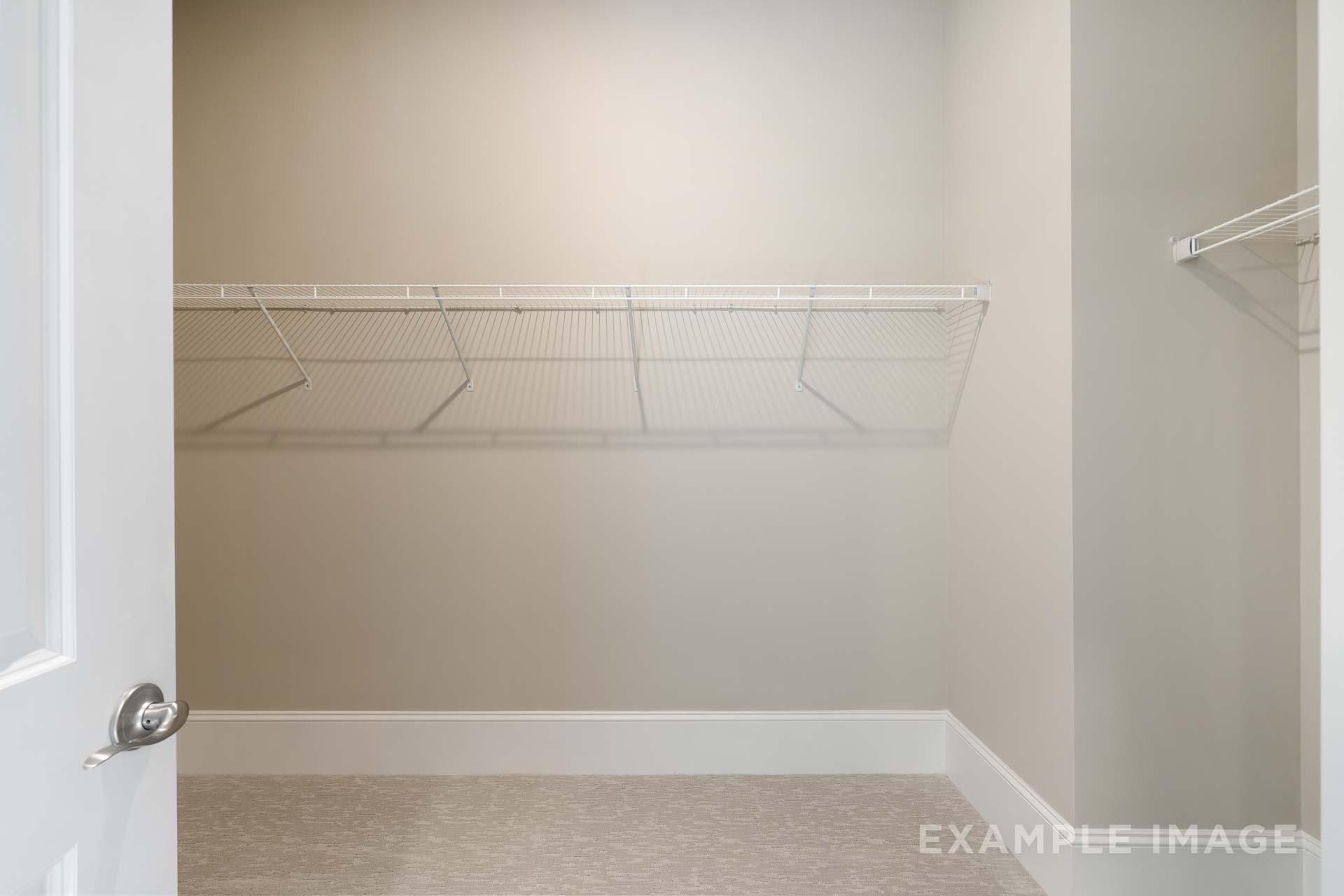 Spacious walk-in closet in The Seaside C with white wire shelving, neutral beige walls, and light carpet flooring