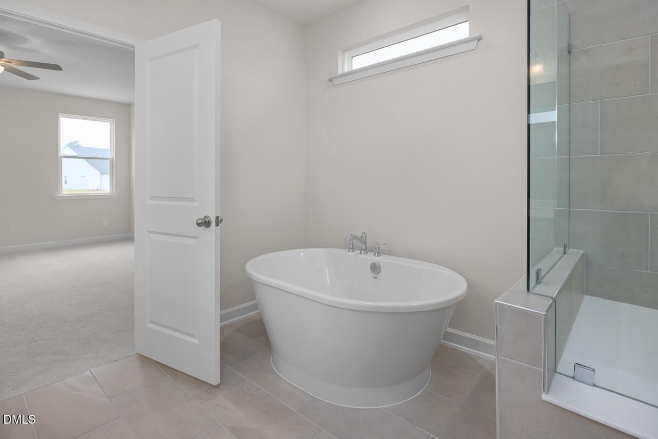 Elegant master bathroom featuring freestanding tub, glass shower, and neutral tile in Davidson Homes The Cypress D II, Angier, NC