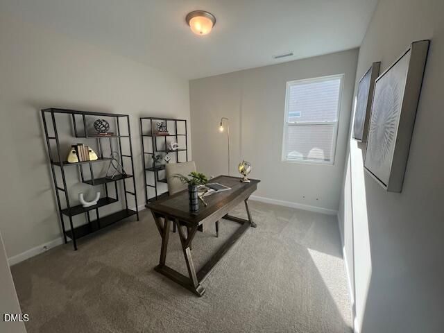 Cozy home office with wooden desk, black metal bookshelves, and natural window light in Davidson Homes The Preston A, Lillington, NC