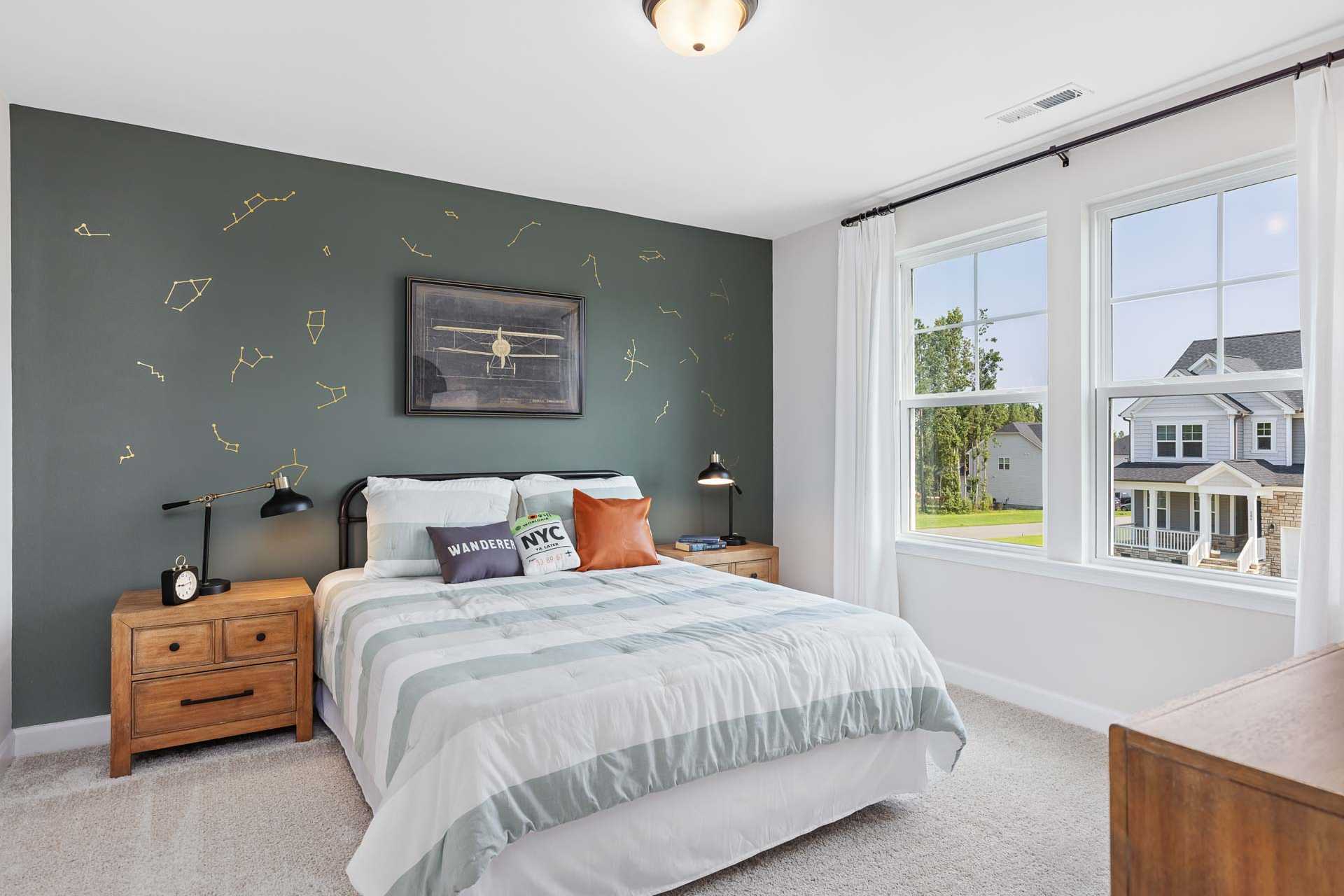 Cozy kids bedroom in Sierra Heights Clayton NC with green constellation wall, model plane art, and striped adventure bedding