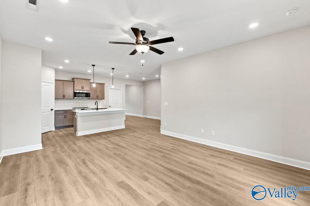 Open-concept living room and kitchen with wood-look flooring in The Camilla C floor plan at The Retreat at Cain Park.