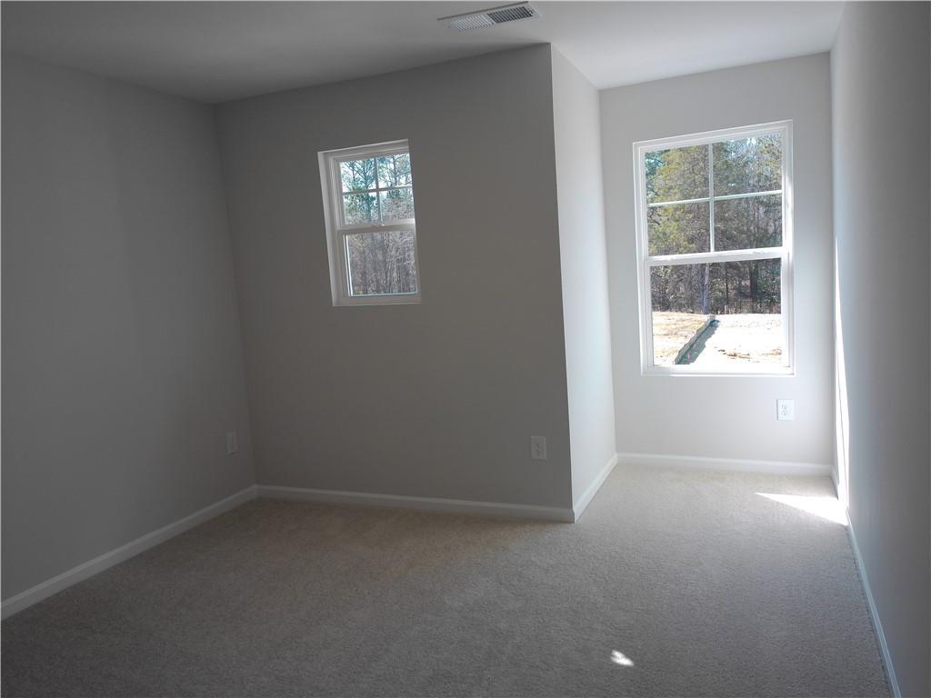 Bright secondary bedroom with large window, light gray walls, and carpet in The Marion C by Davidson Homes, Winder, GA