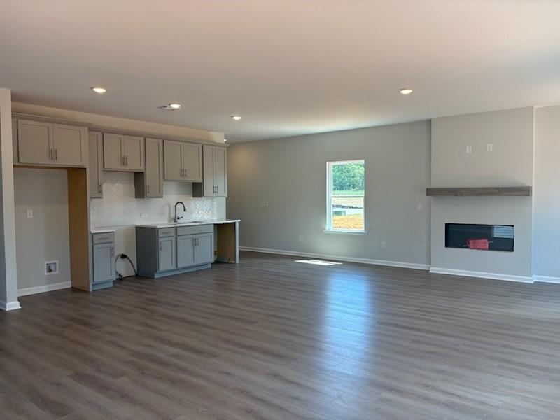 Modern open-concept kitchen with gray cabinets, white backsplash, and family room gas fireplace in The Rabun A, Winder, Georgia