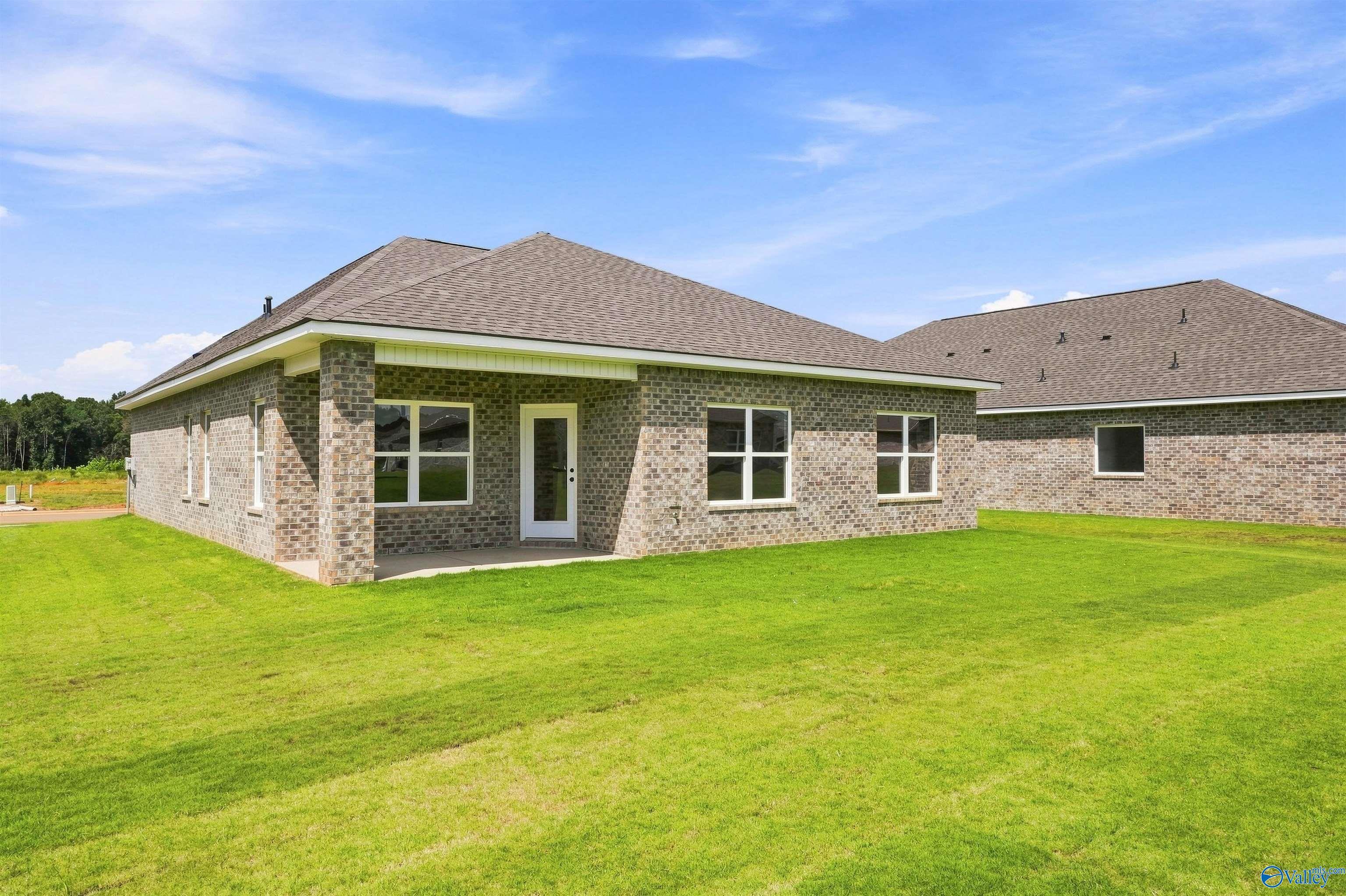 Brick exterior with covered patio and fenced backyard of Davidson Homes The Franklin C in Wood Trail, Toney, Alabama