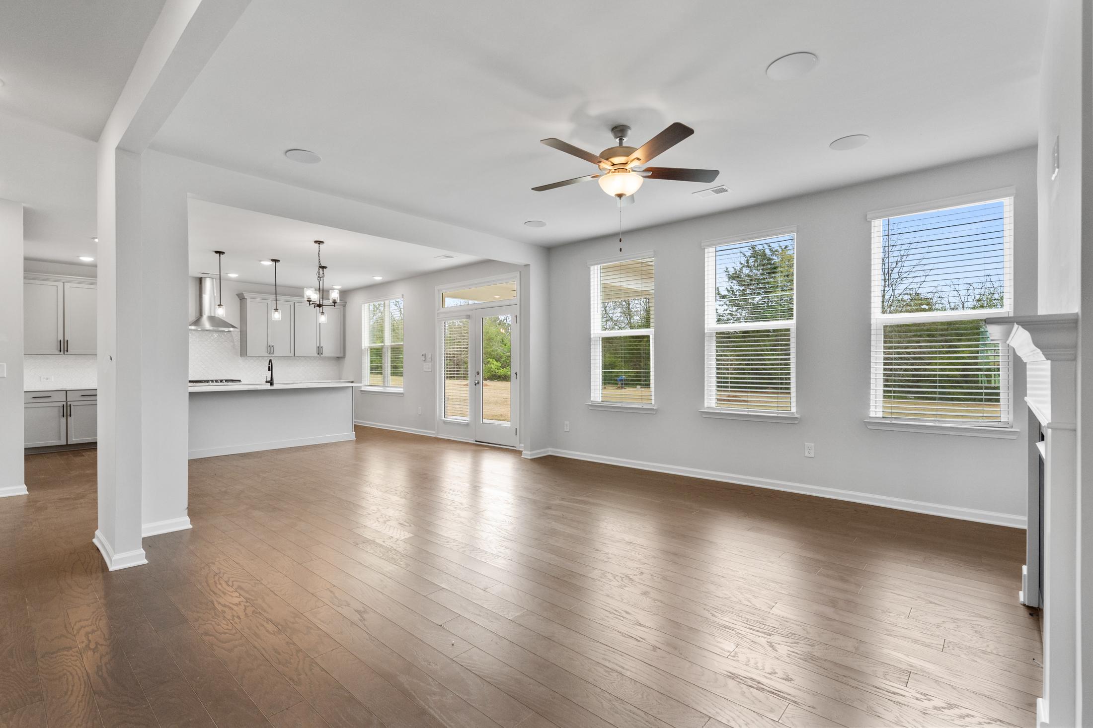 Spacious open-concept living and kitchen at Reverie at East Lake in McDonough GA with hardwood floors, ceiling fans, and large windows