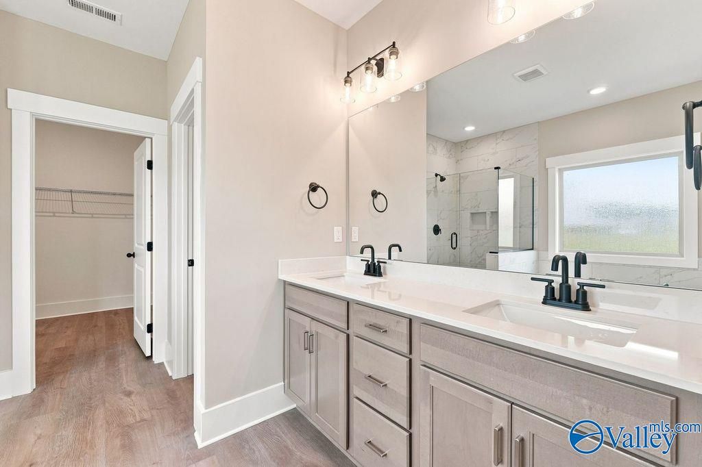 Modern master bathroom with dual vanity, glass shower, and walk-in closet in The Rockford home at Cain Park, Hartselle, AL.
