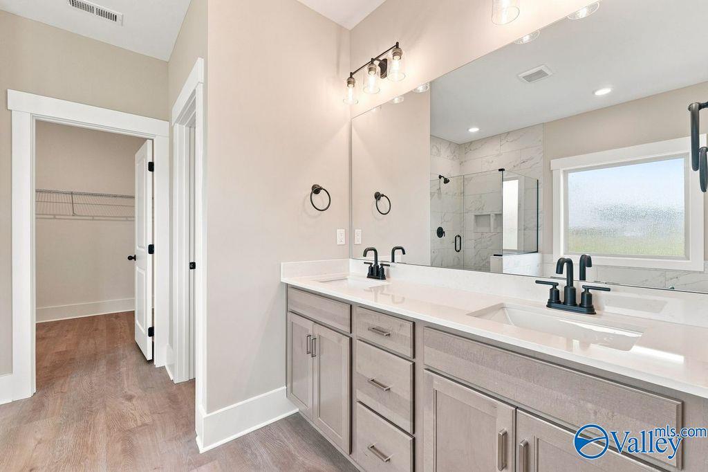Modern master bathroom with dual vanity, glass shower, and walk-in closet in The Rockford home at Cain Park, Hartselle, AL.
