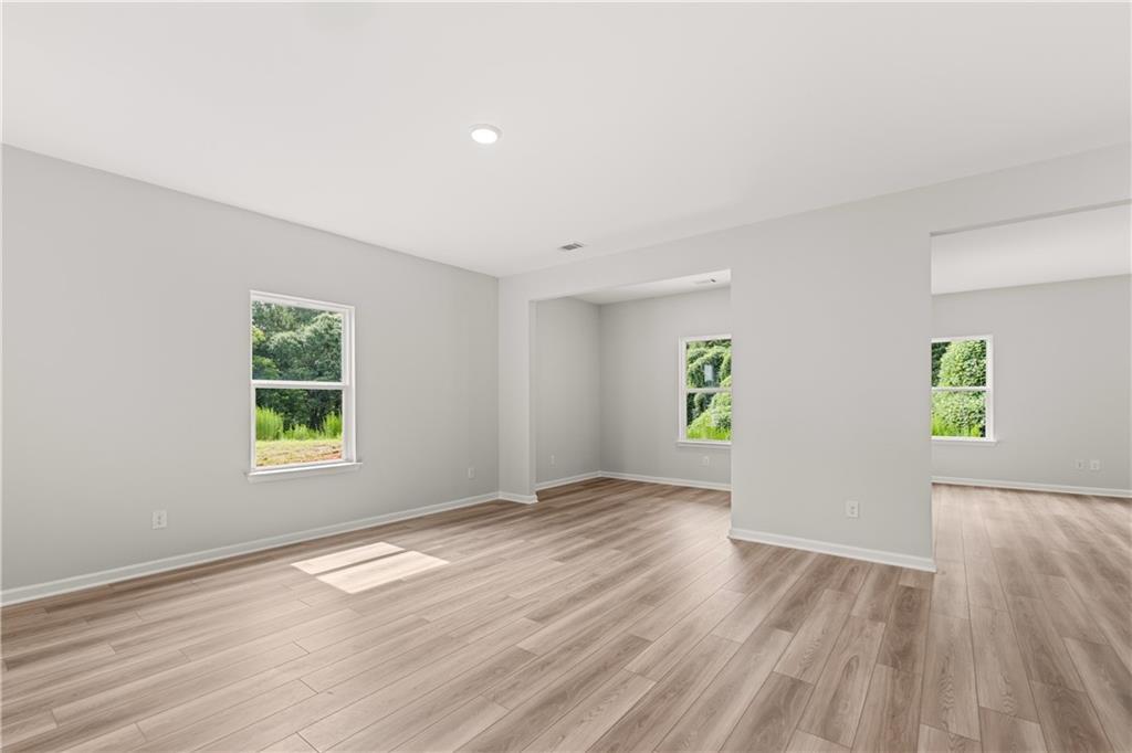 Spacious open-concept living area with wood-style flooring in The Russell A floor plan at Cedar Farms in Winder, Georgia.