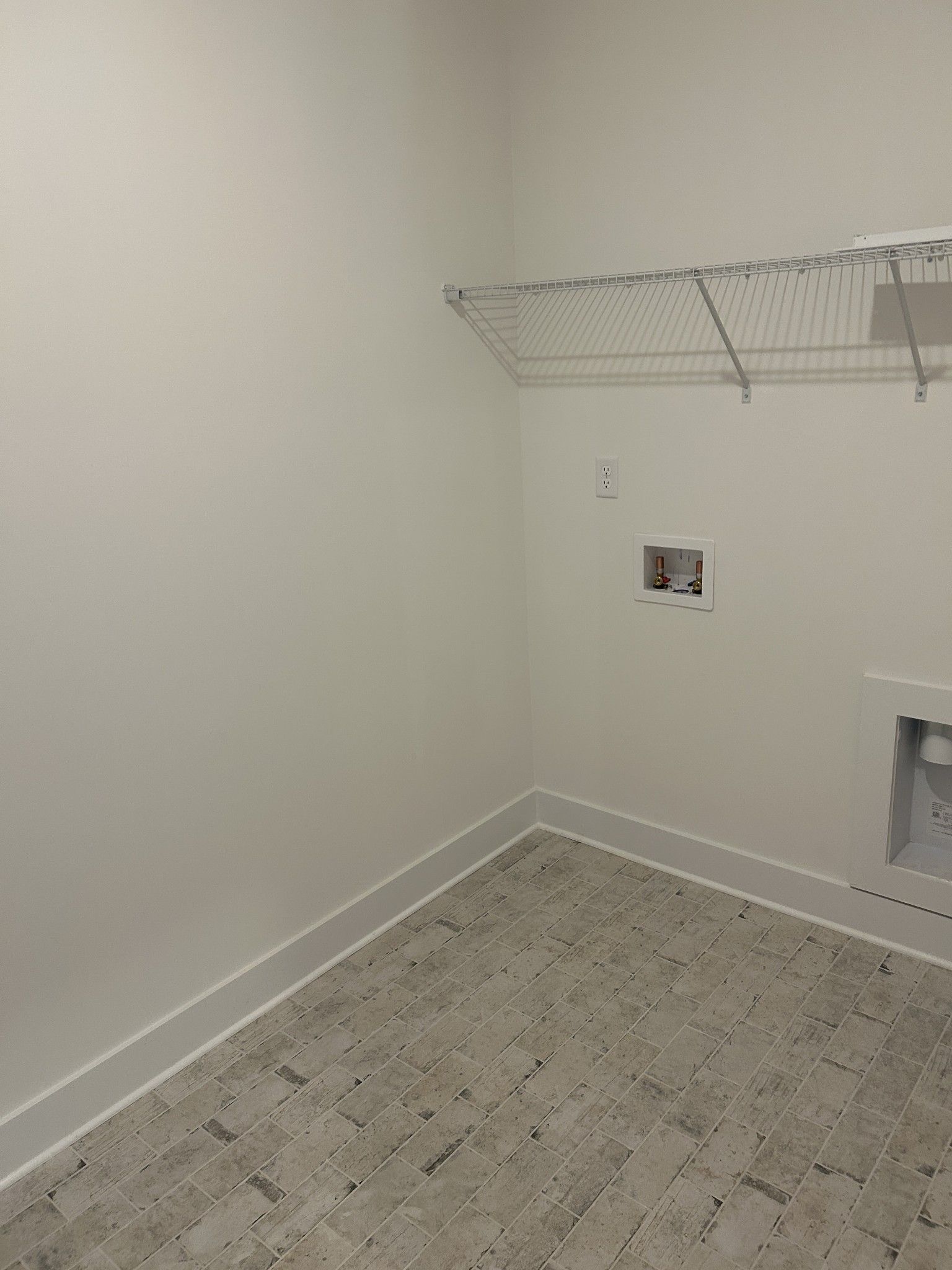Spacious laundry room featuring utility sink, wire shelving, and gray plank flooring in The Ridgeport F by Davidson Homes, Mt. Juliet, TN