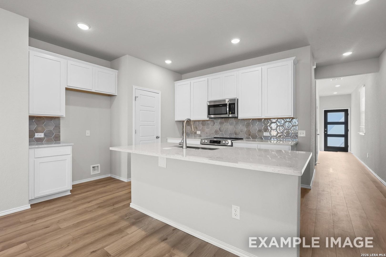 Modern white kitchen with quartz island, stainless appliances, geometric subway backsplash in Davidson Homes The Colorado D, San Antonio