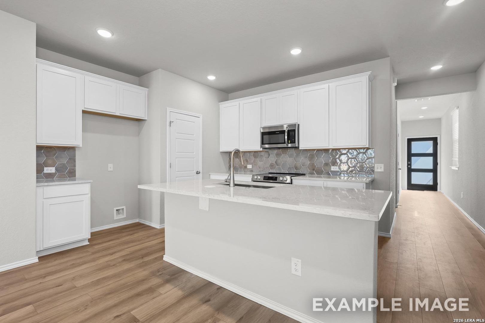 Modern white kitchen with quartz island, stainless appliances, geometric subway backsplash in Davidson Homes The Colorado D, San Antonio