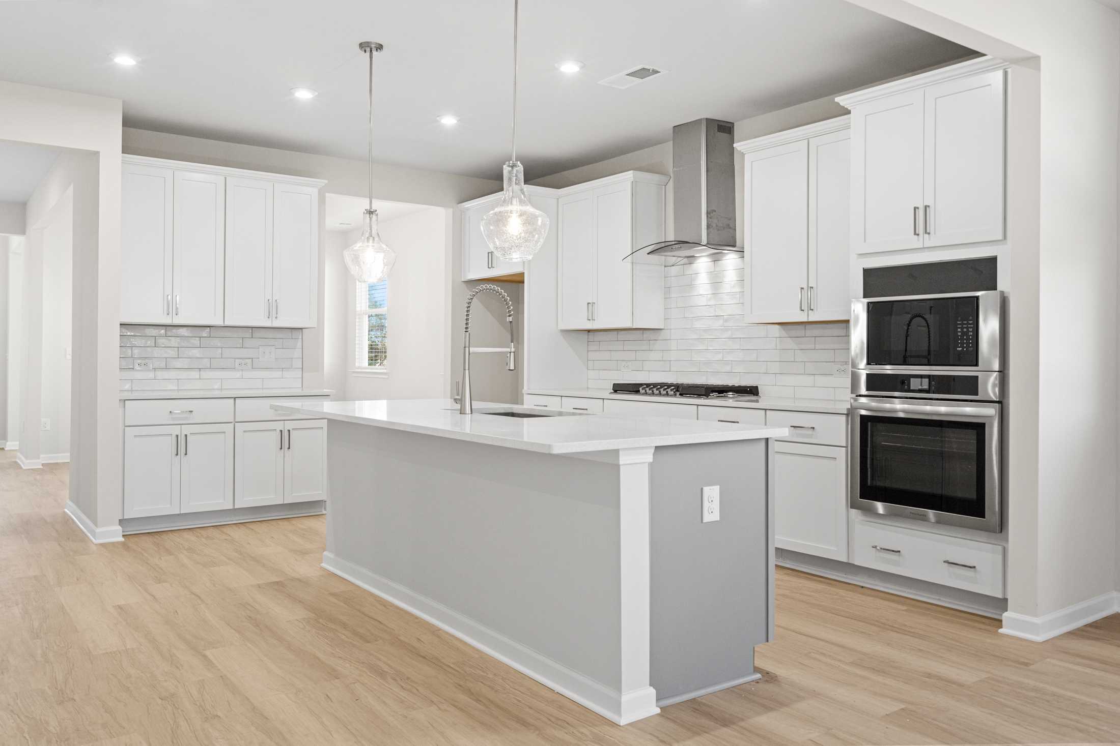 Modern kitchen in The Glenwood A by Davidson Homes featuring white shaker cabinets, large gray island, subway tile backsplash