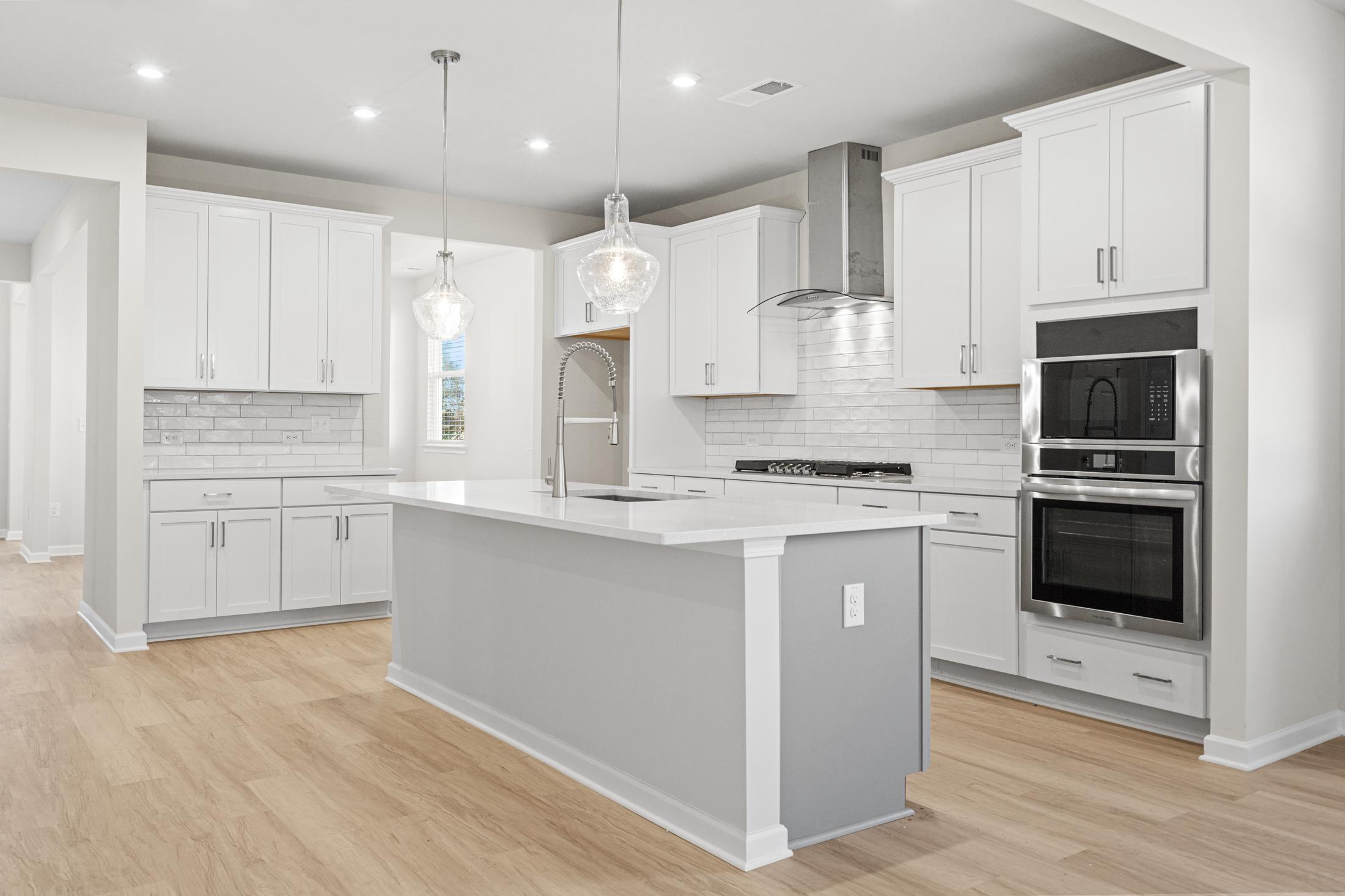Modern kitchen in The Glenwood A by Davidson Homes featuring white shaker cabinets, large gray island, subway tile backsplash