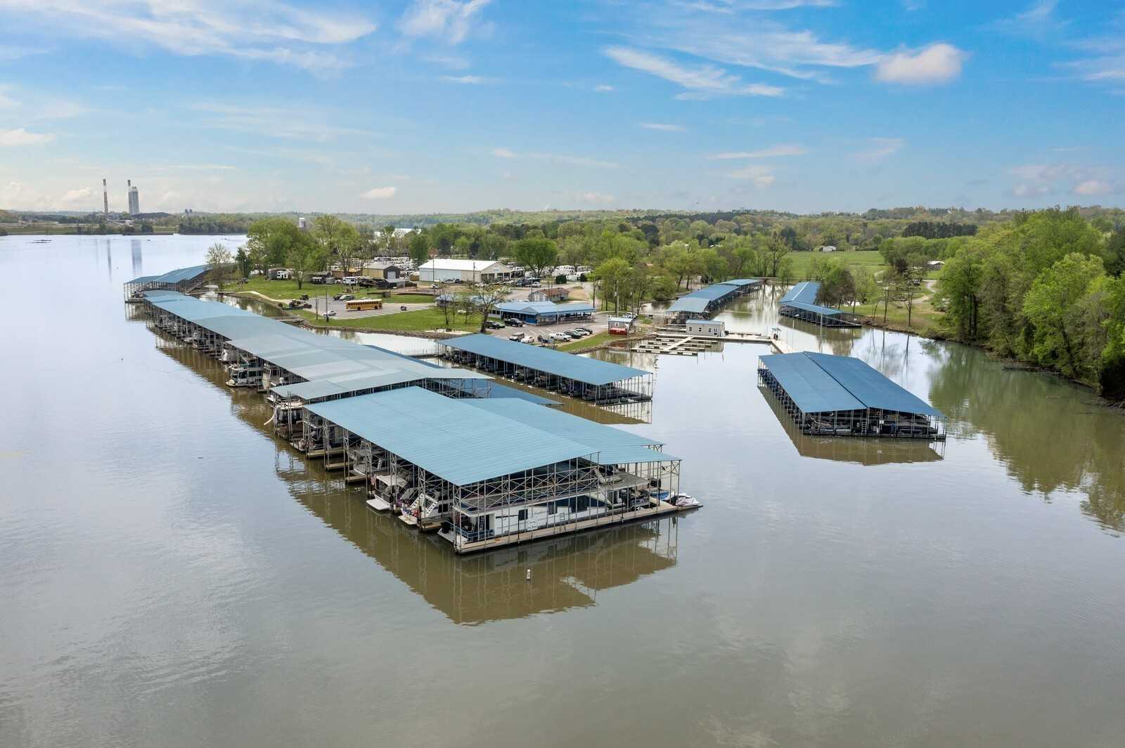 Aerial view of covered boat slips at riverside marina in Gallatin, Tennessee, with calm waters, lush trees, and blue skies