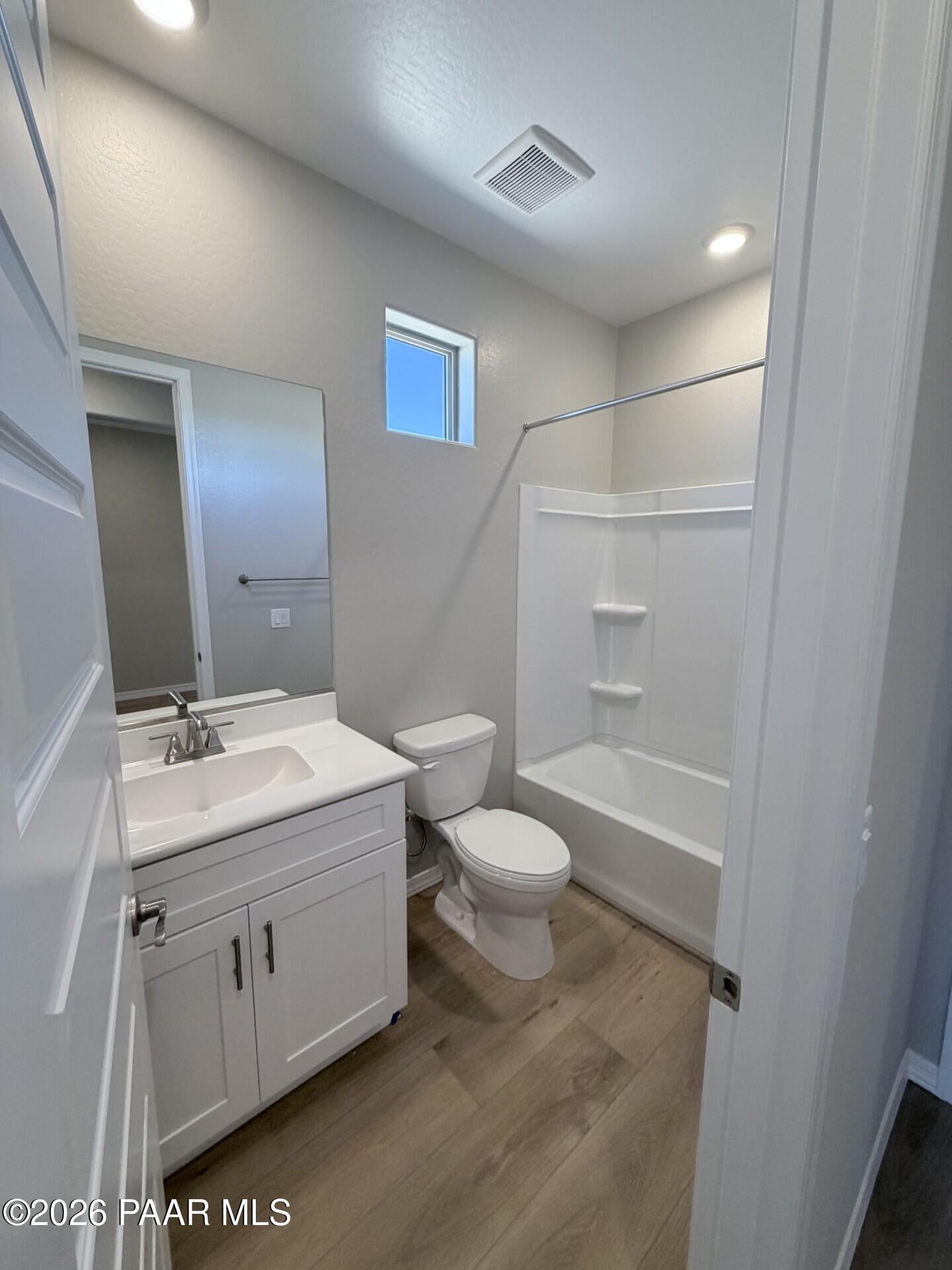 Modern bathroom with white vanity, tub-shower combo, and wood-look floors in The Frontier A floor plan at Pronghorn Ranch.