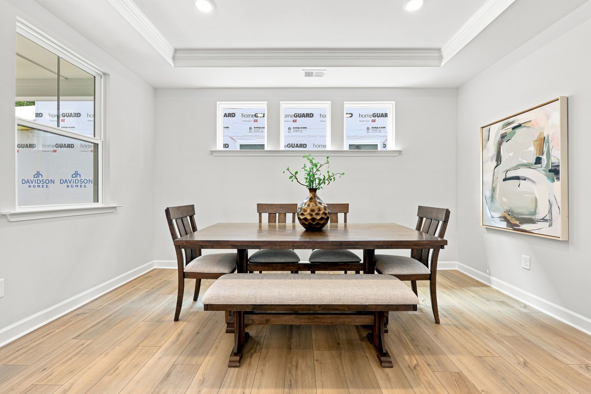 Bright, modern dining room in The Jordan A by Davidson Homes featuring a farmhouse table and tray ceiling design.