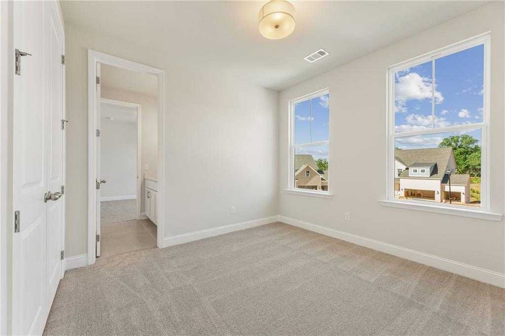 Bright secondary bedroom with en-suite bath, neutral walls, and neighborhood views in Davidson Homes The Danbury E, Buford, GA