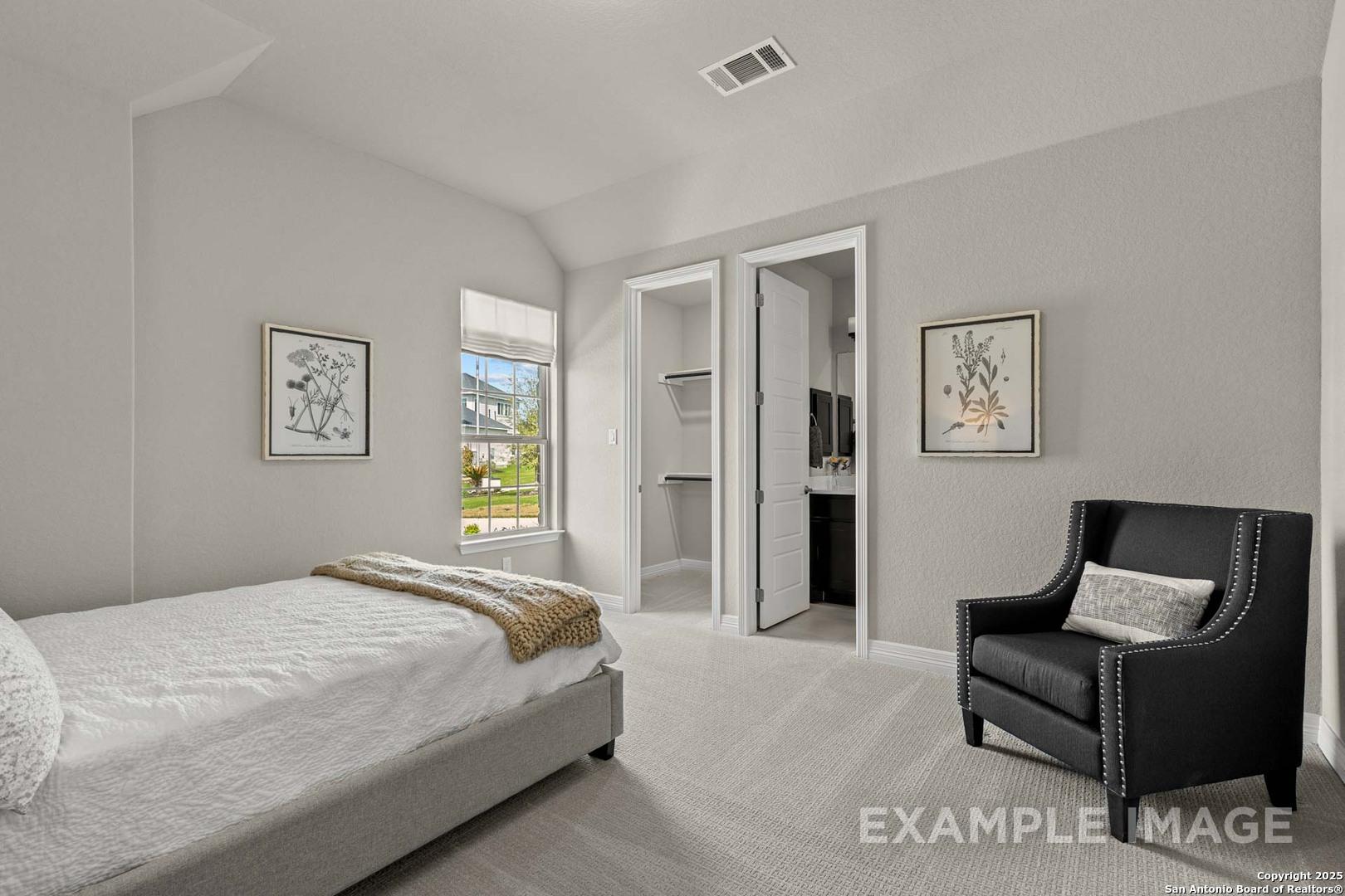 Cozy secondary bedroom with queen bed, leather armchair, botanical art, walk-in closet in Davidson Homes The Summerlin B, Castroville, Texas