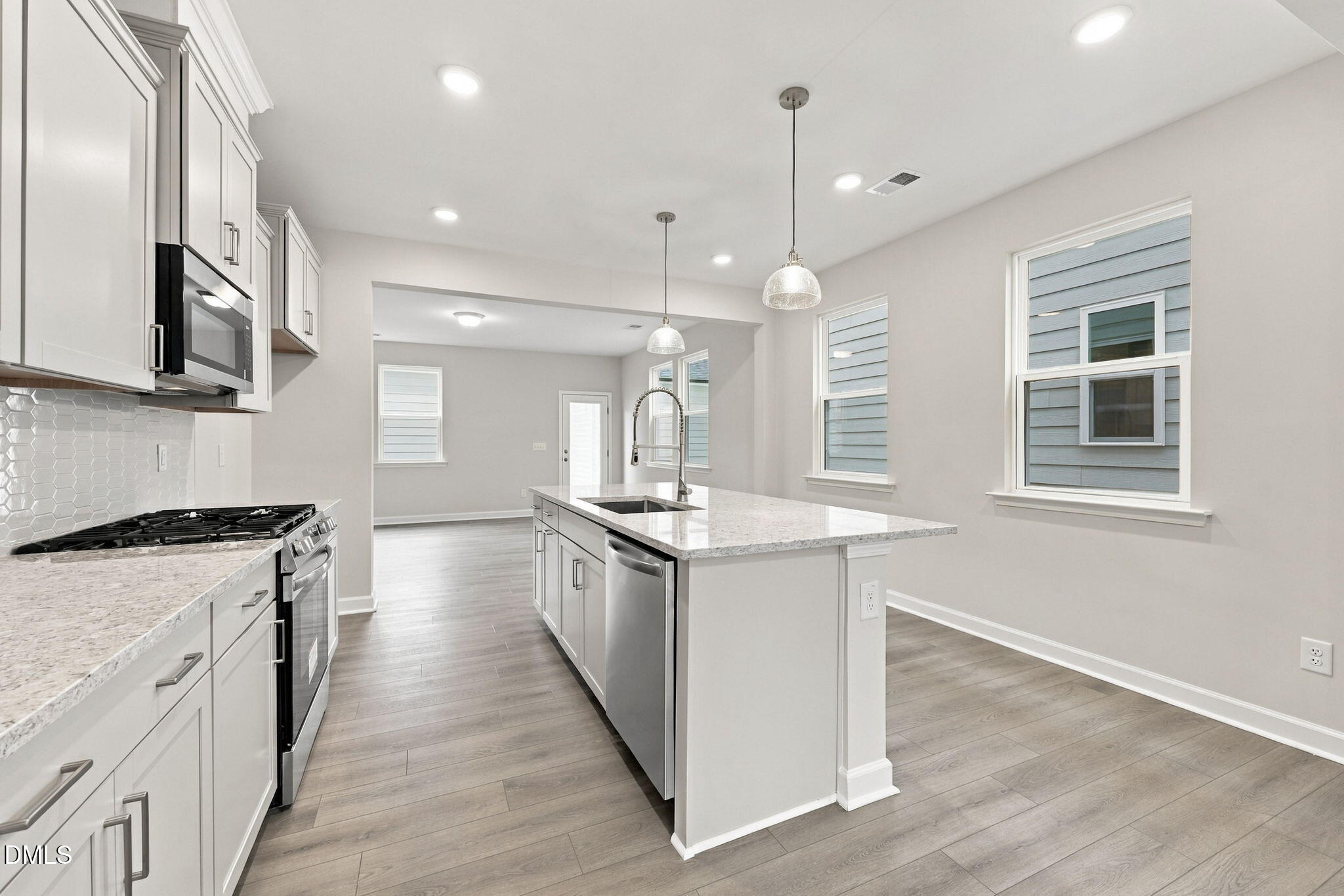 Bright open-concept kitchen with white cabinetry, granite island, and stainless appliances in Davidson Homes The Alexander B, Knightdale NC