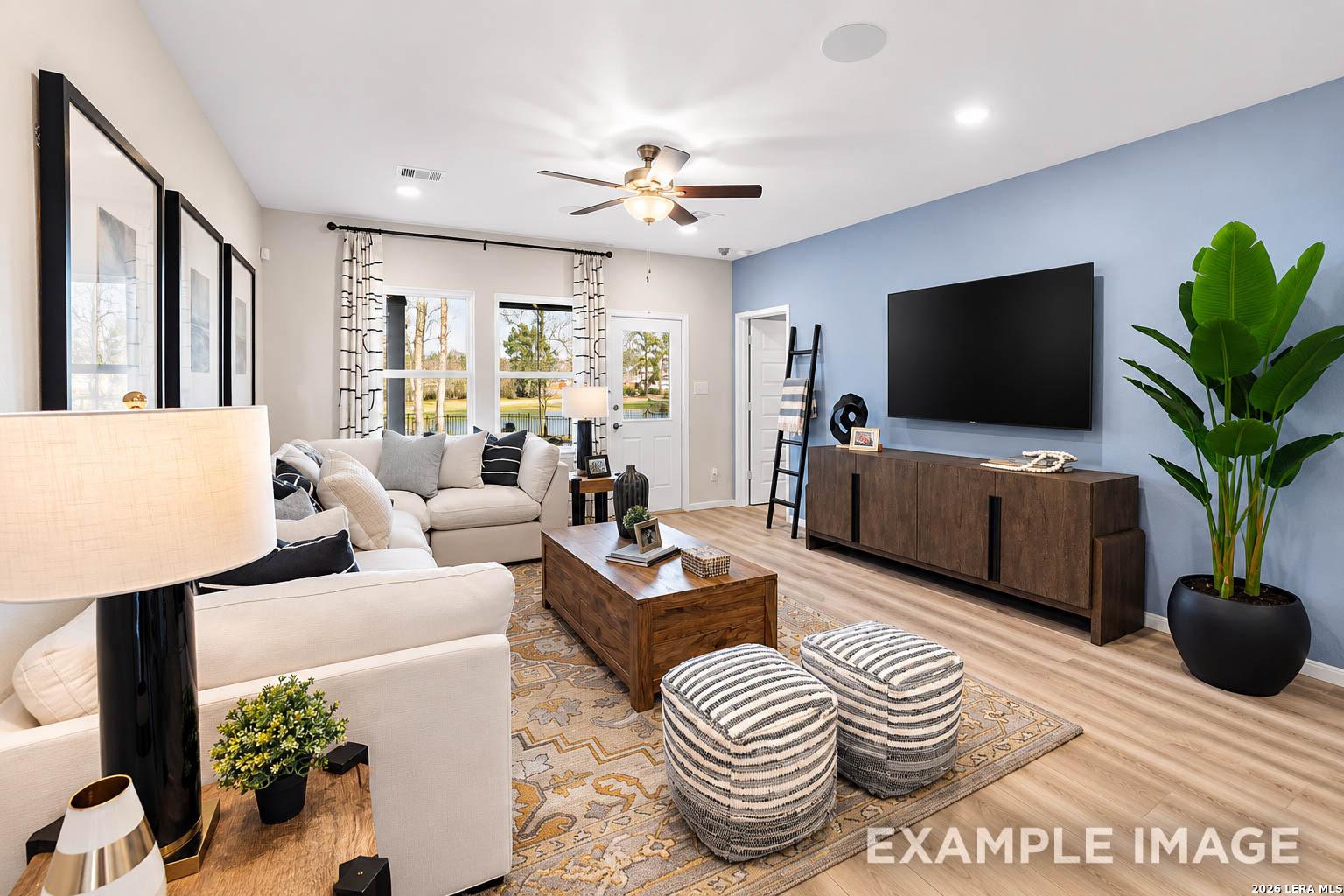 Modern living room with blue accent wall, white sectional, and wood decor in The San Marcos F, Rayburn Valley, San Antonio.