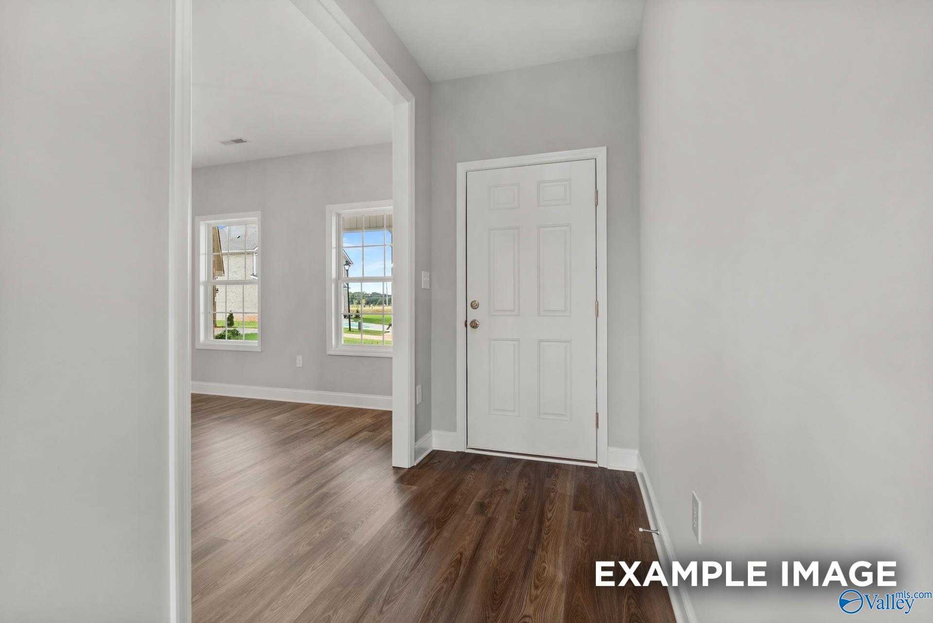 Bright hallway with hardwood floors, white paneled door, and windows overlooking green yard in Davidson Homes Shelby B, Athens AL