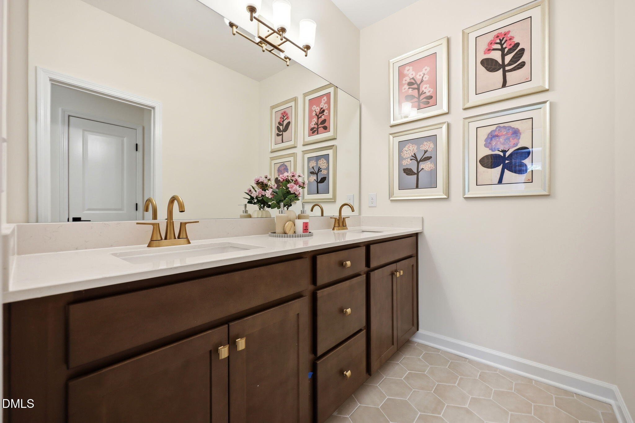 Double vanity bathroom with dark cabinets, gold hardware, and floral wall art in The Aspen B at Wendell Ridge, NC.