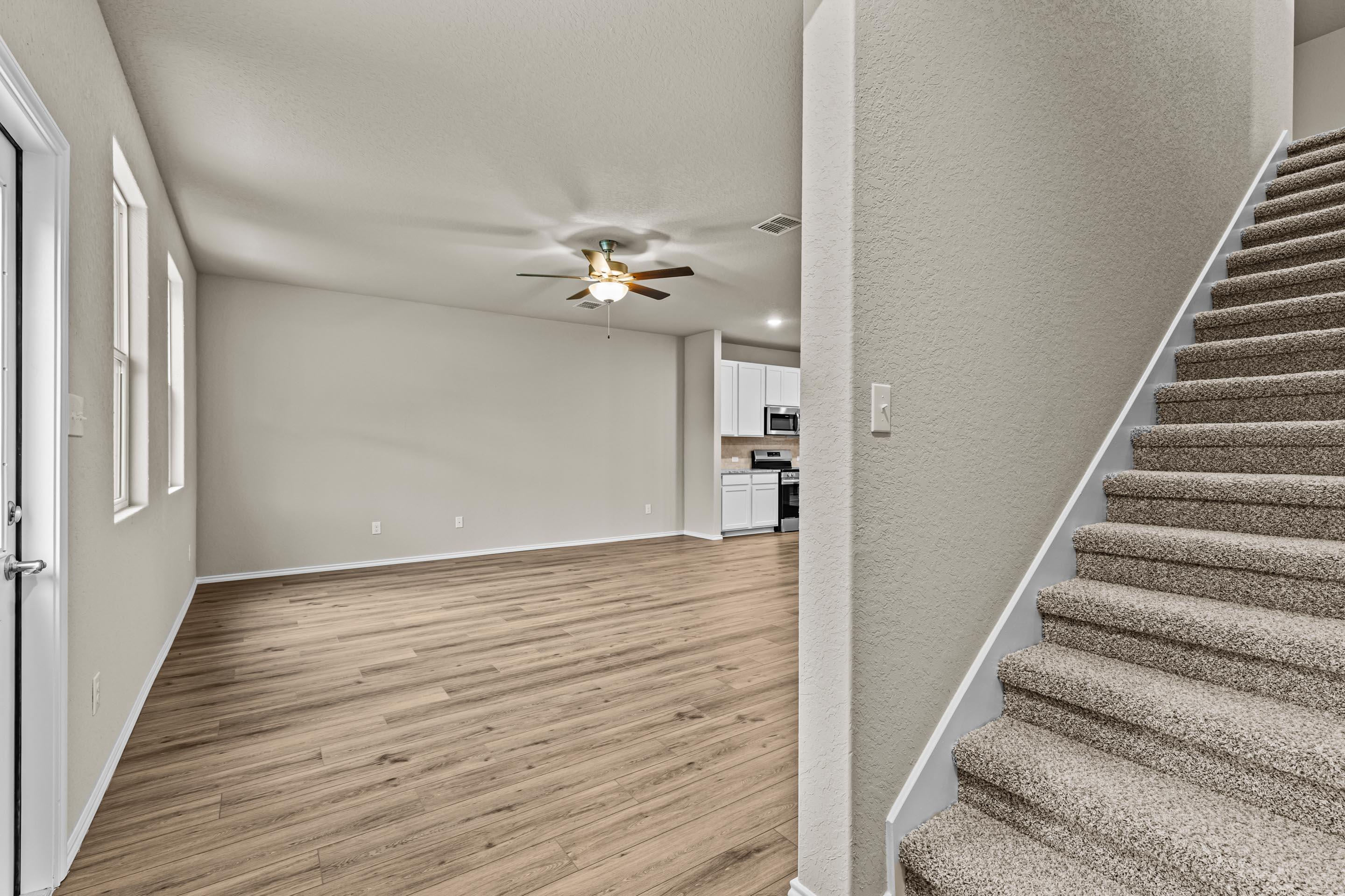 Spacious entry foyer with hardwood floors, ceiling fan, and carpeted staircase in Davidson Homes The Douglas F, San Antonio, Texas