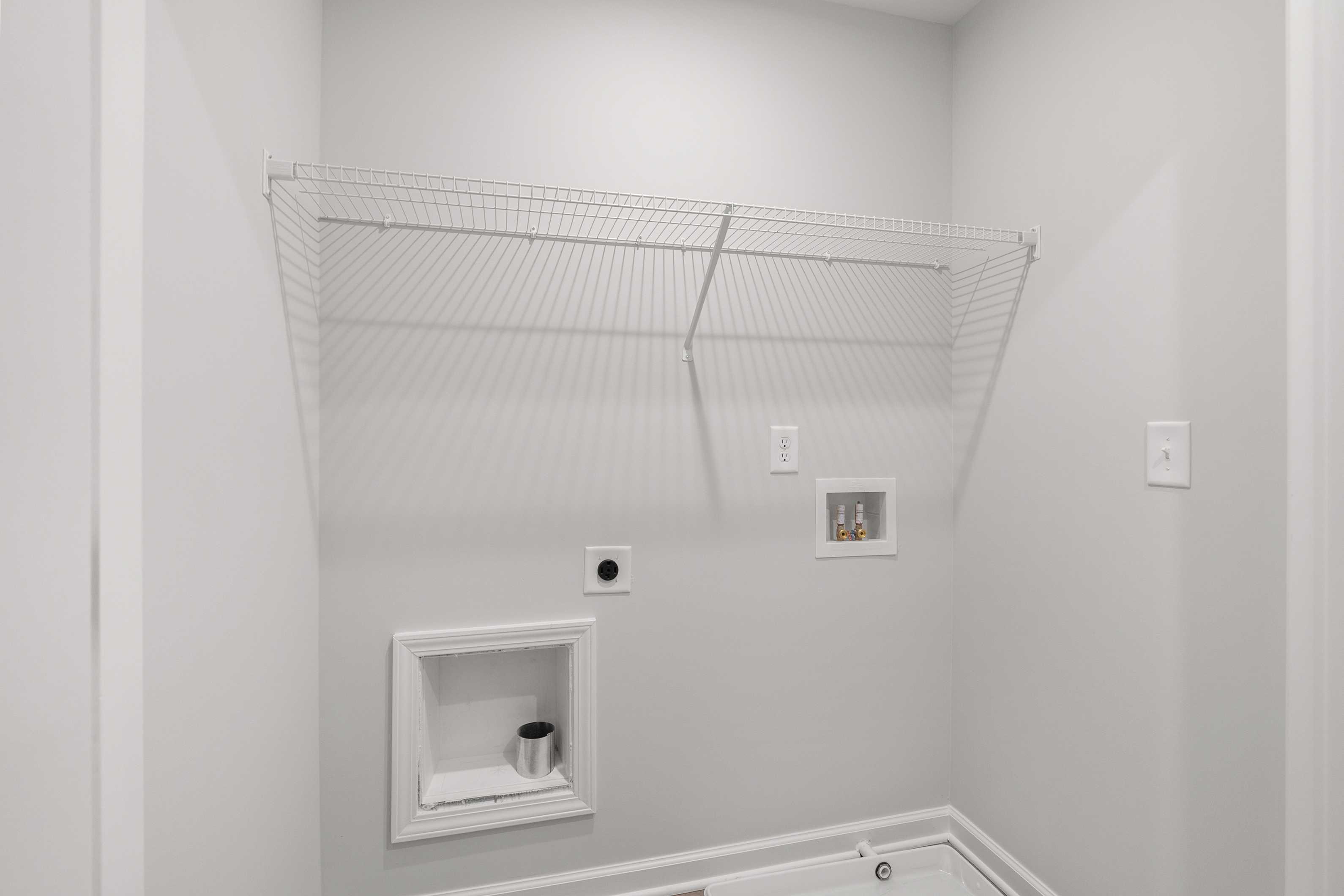 Laundry closet in The Durant A home with wire shelving, dryer vent box, electrical outlets, and utility sink on light gray walls