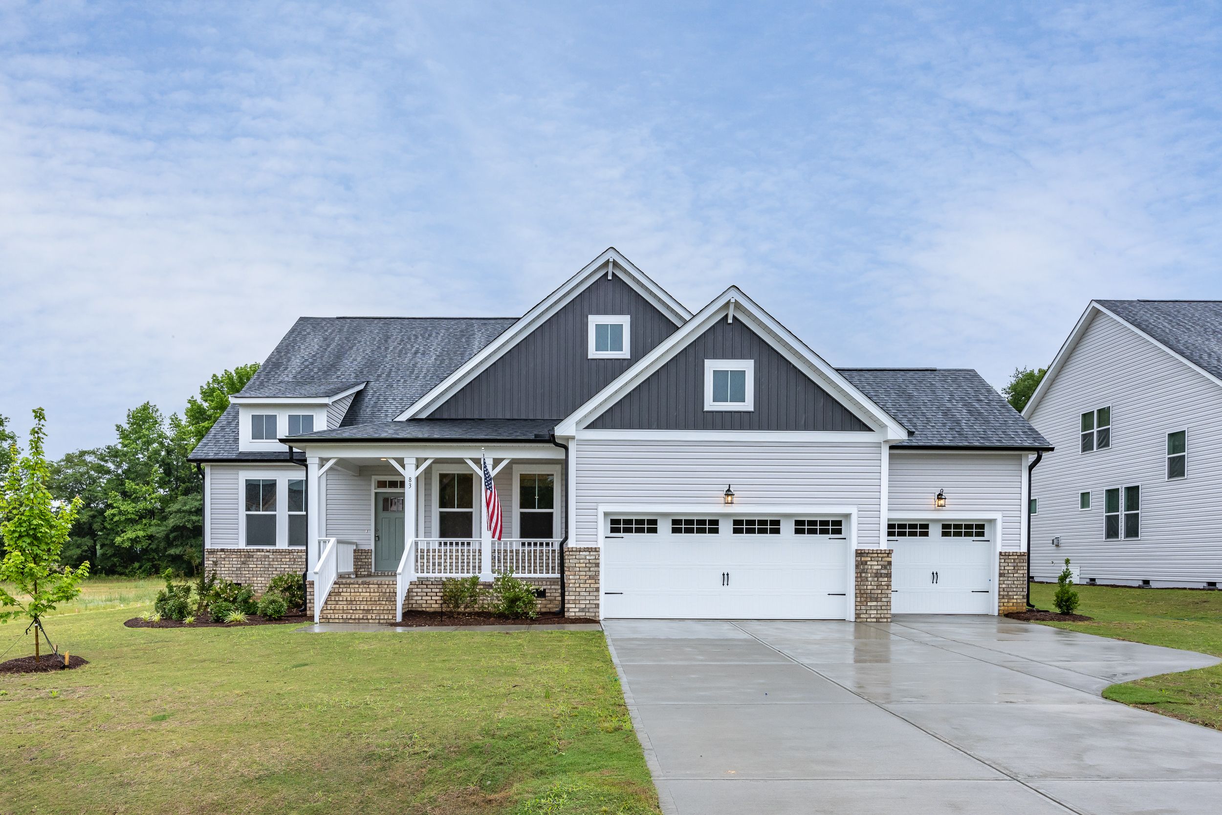 Modern farmhouse exterior at Rockport in Wake Forest, NC by Davidson Homes featuring a covered porch and three-car garage.