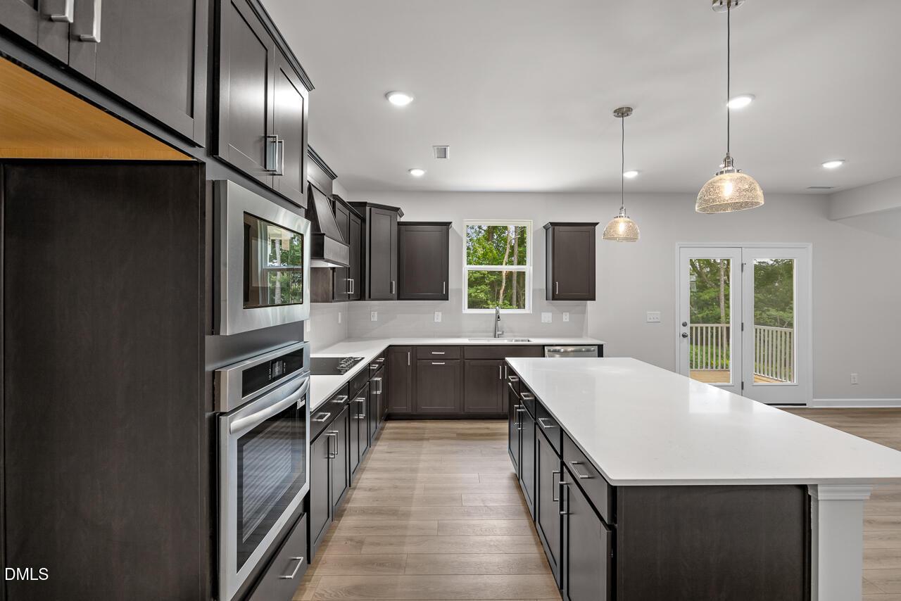 Modern kitchen with dark cabinets, large quartz island, and stainless appliances in The Hickory II B, Wellers Knoll home.
