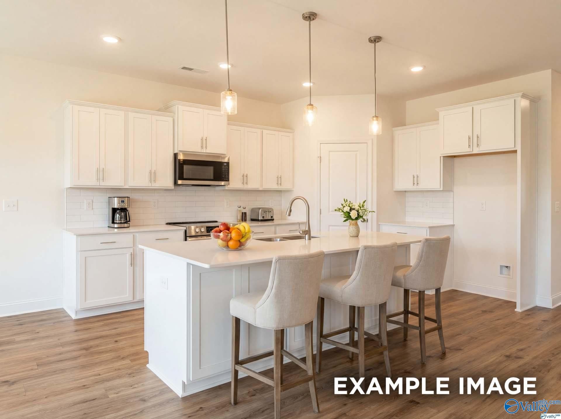 Modern white kitchen with island seating in The Rockford B floor plan at Kendall Downs in Toney, Alabama.